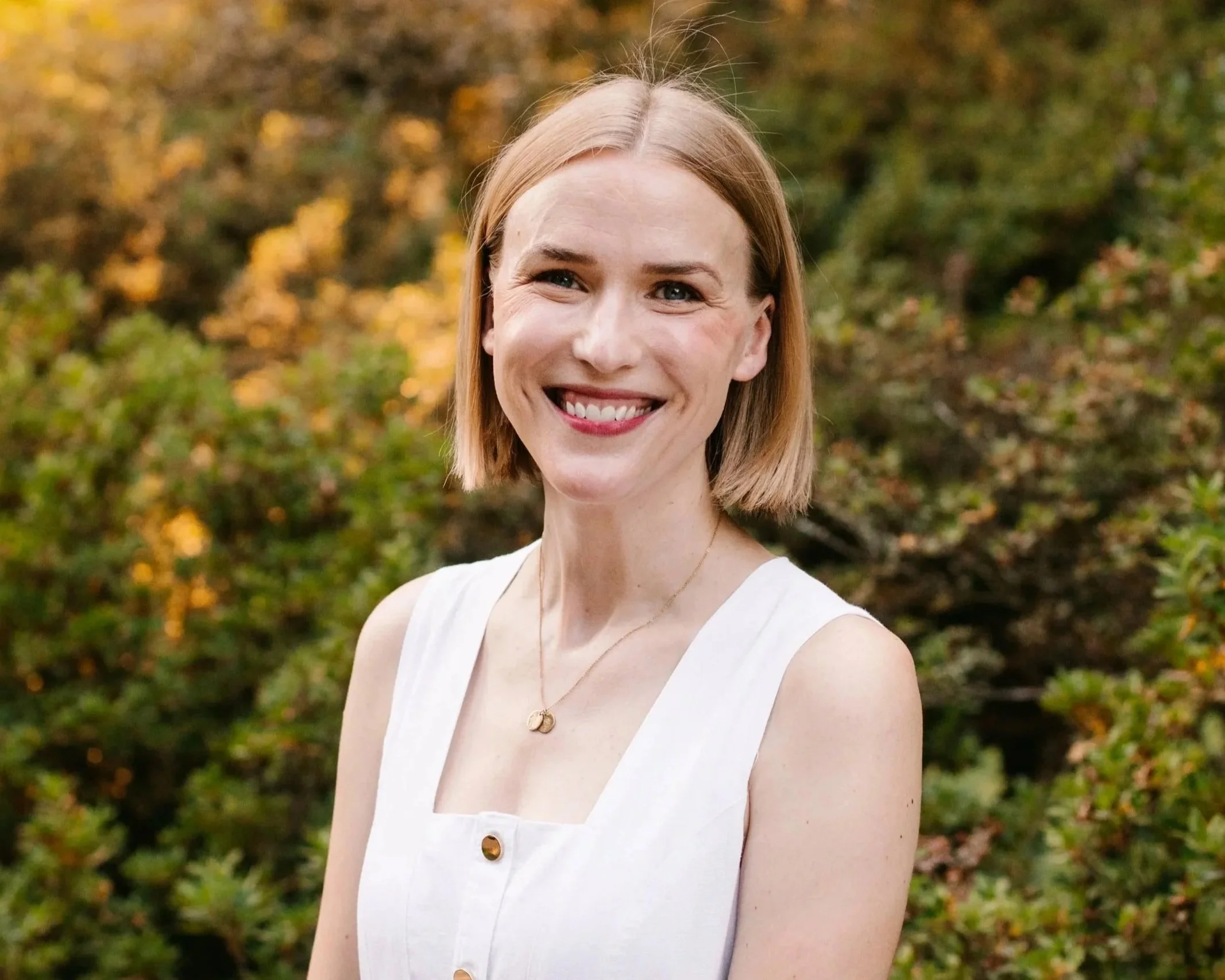 Therapist smiling outdoors in front of autumn foliage