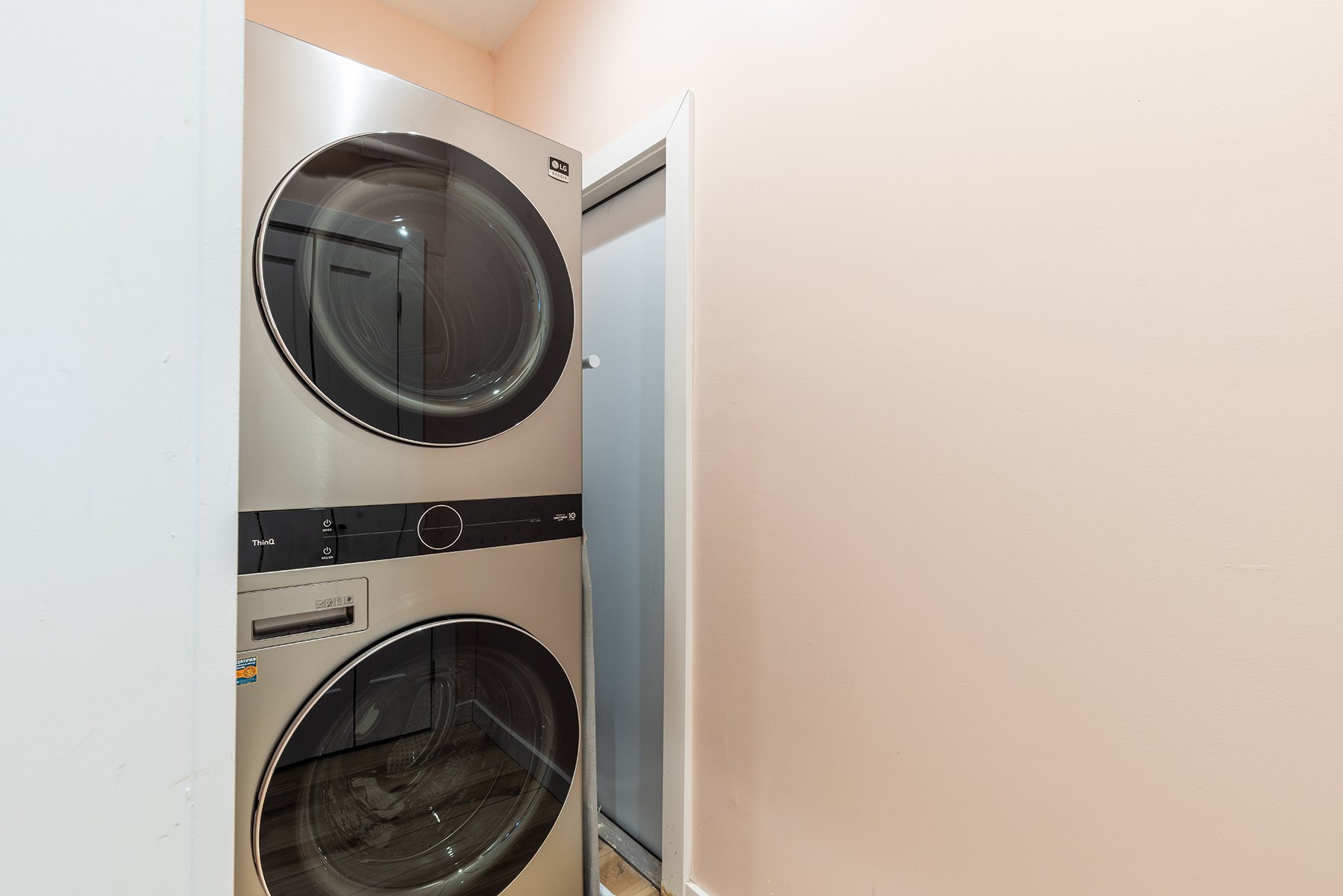 A stacked LG front-loading washer and dryer in a laundry room, with a door open nearby.