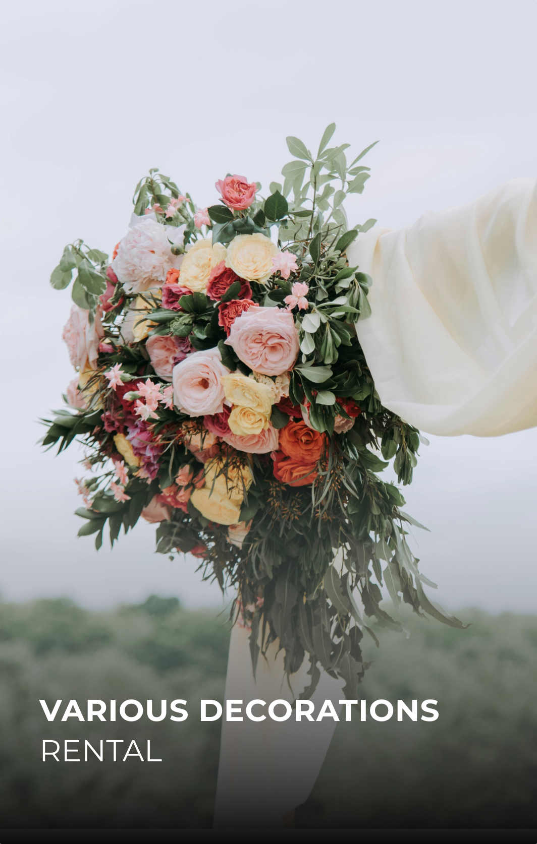 Bouquet de fleurs colorées avec roses et feuillage, porté par une personne en tenue claire, avec un fond nuageux et déclinant vers un paysage flou