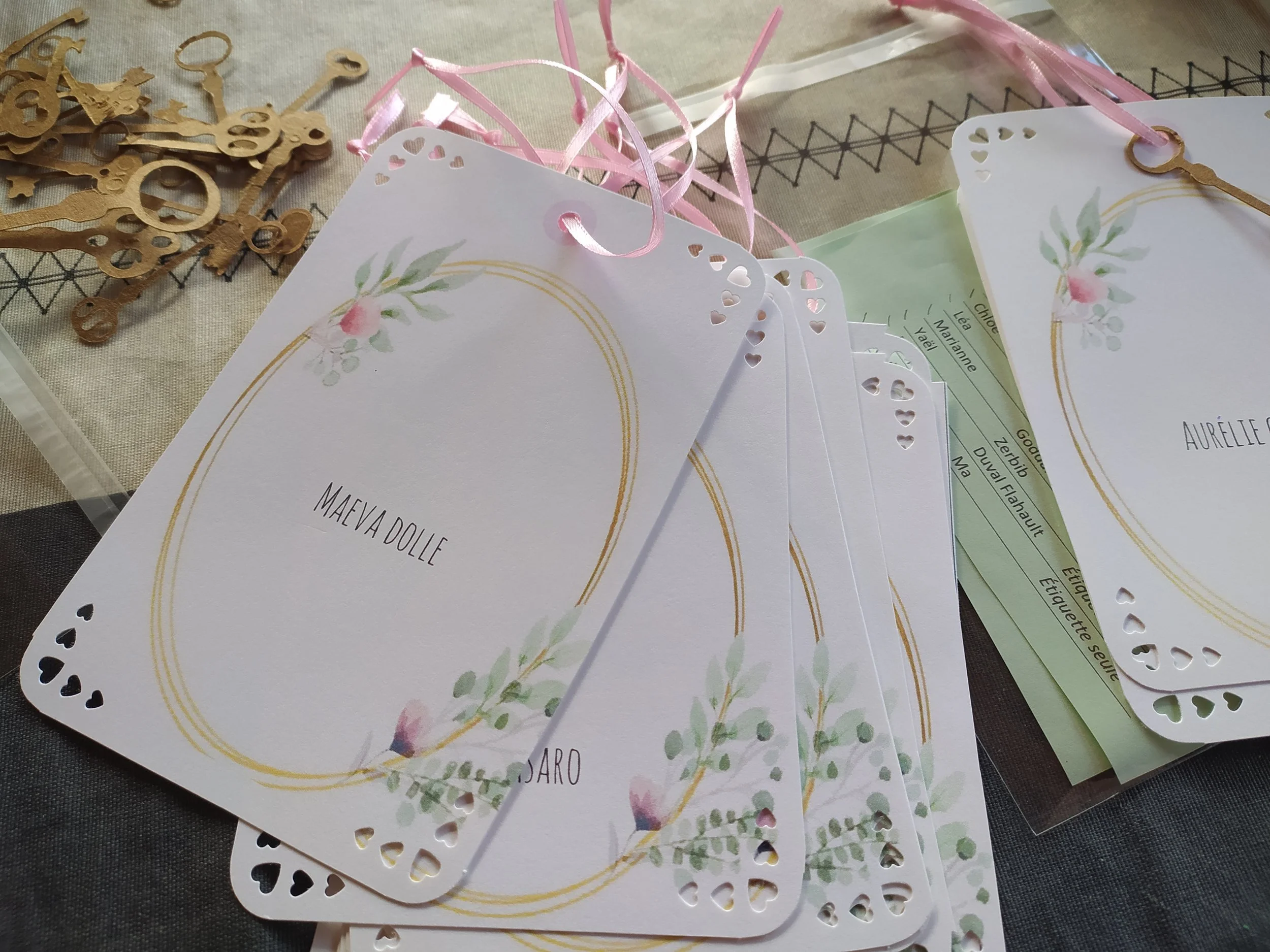 Cartes de félicitations avec motifs floraux et rubans roses, entourées de petits éléments en bois