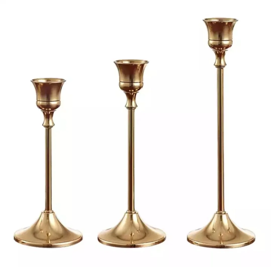 Trois candélabres en métal doré de différentes hauteurs alignés.