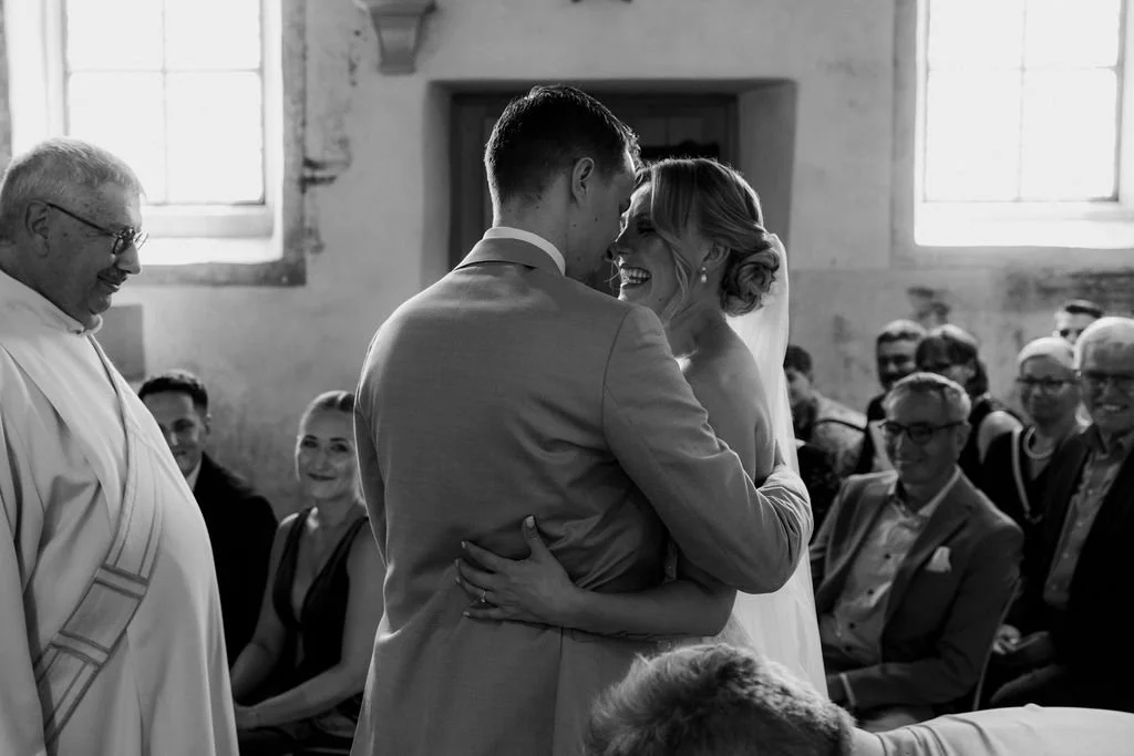Ein Brautpaar aus der Schweiz heiraten und der Kirche und lachen sich an. Die Hochzeitsfotografin hat diese Hochzeit festgehalten mit Kamera in Luzern.