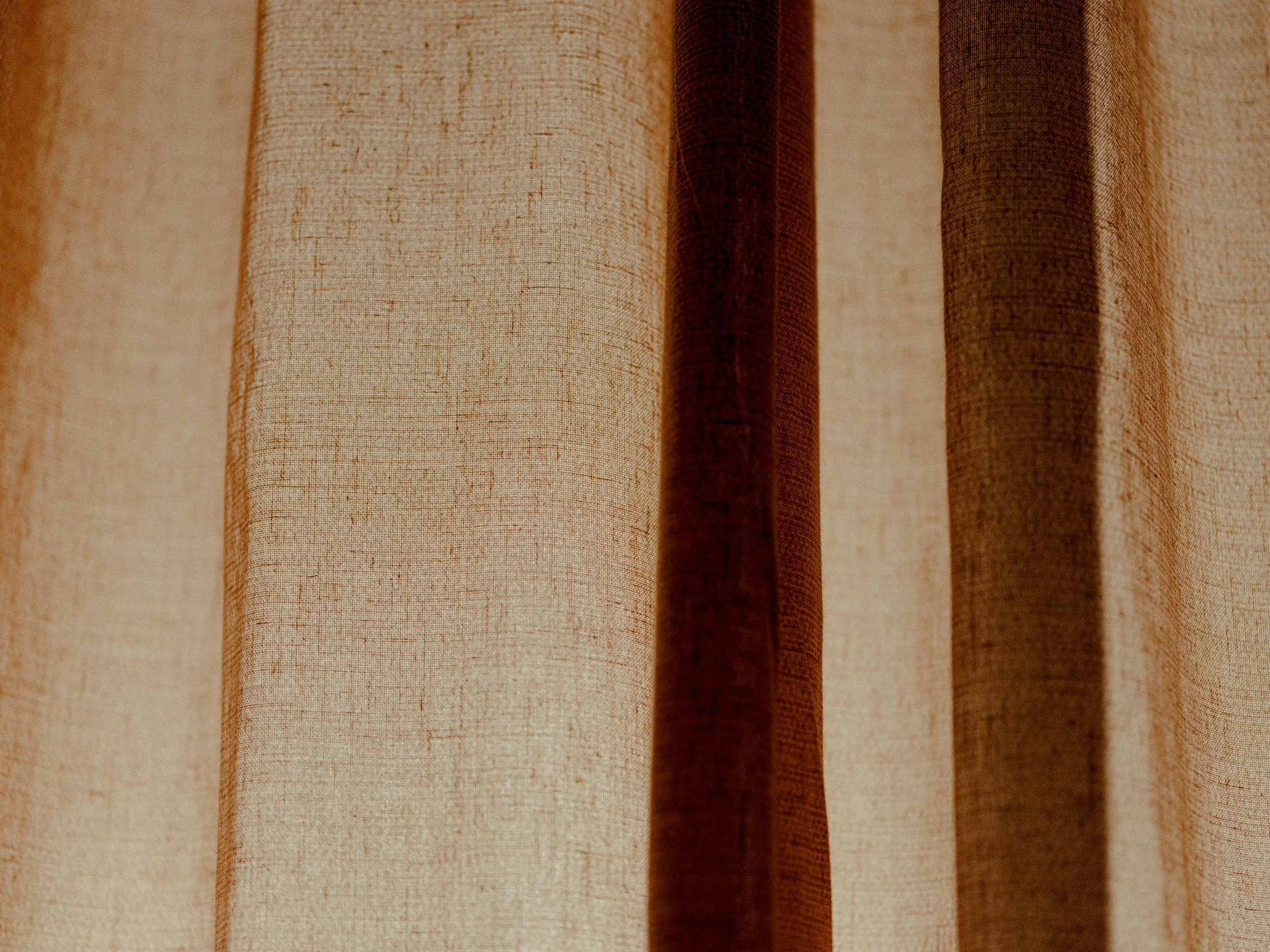 Close-up of beige and brown fabric curtains hanging vertically.