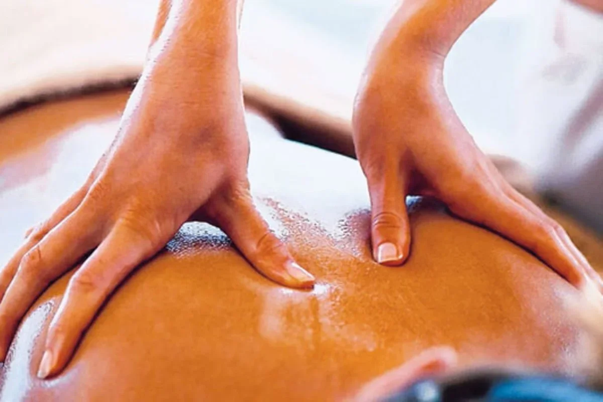Close-up of a person receiving a massage, focusing on their back with hands applying pressure.