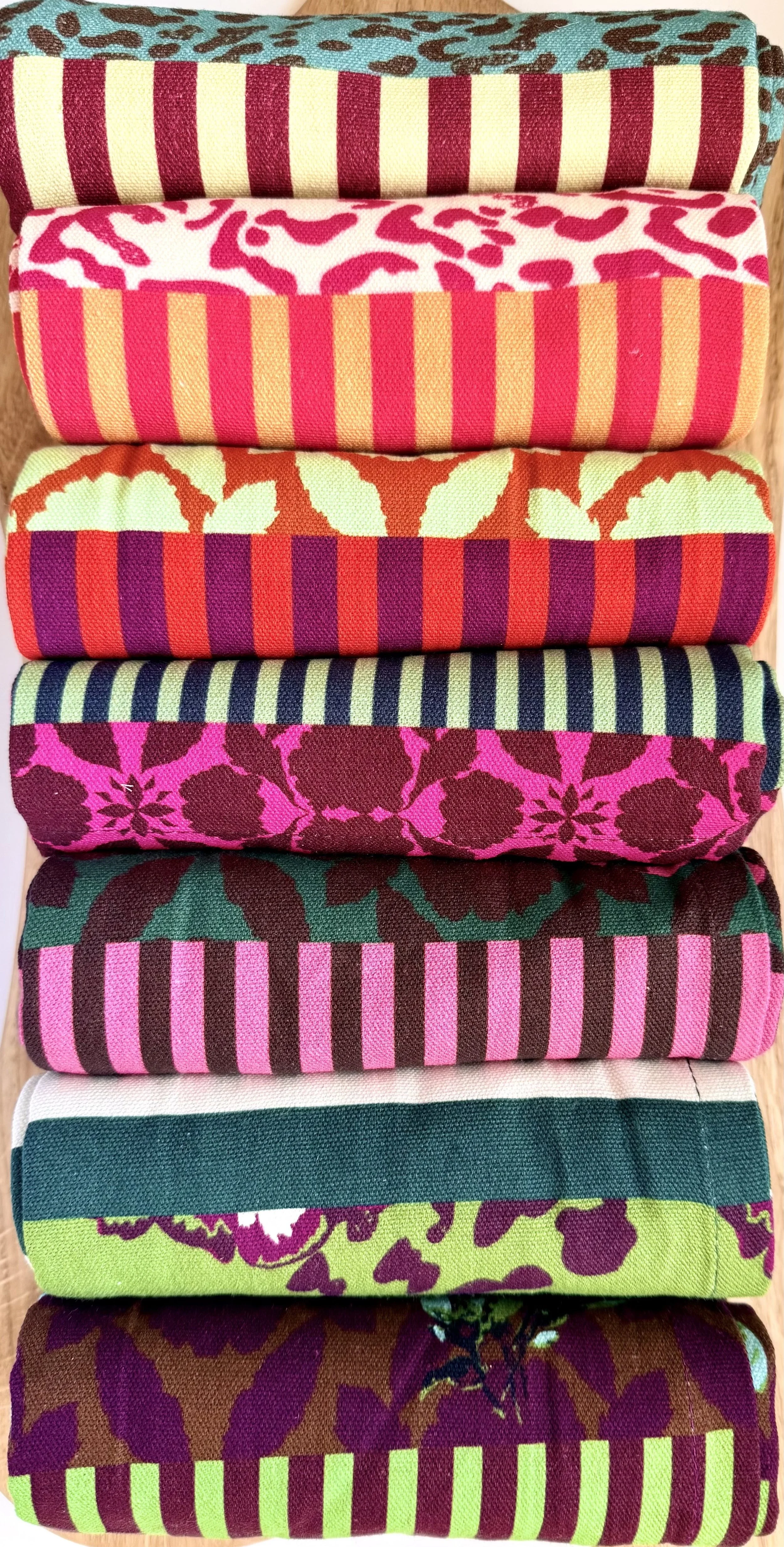 Stack of folded cotton dish towels in bold stripes and maximalist florals, colorful kitchen home decor by artist Lynette Reed