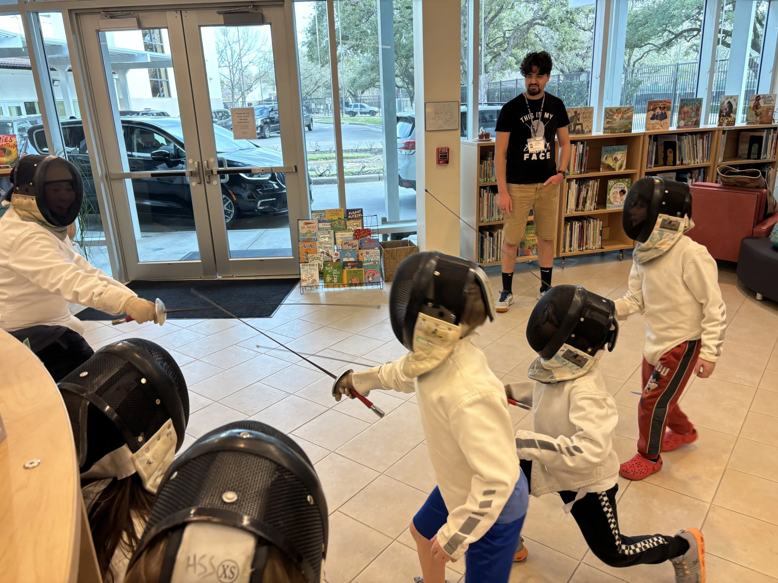 Three small kids team up against one larger kid in the library at the Post Oak School