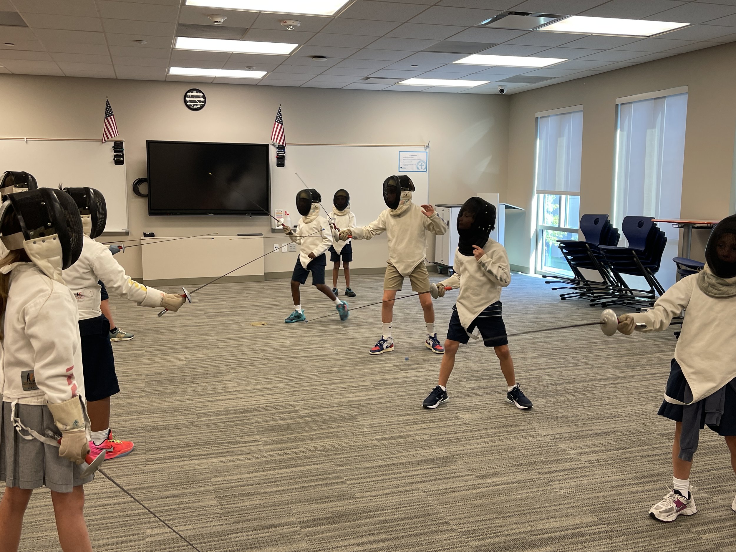 A group of children wearing protective equipment fence with each other at Annunciation Orthodox School.