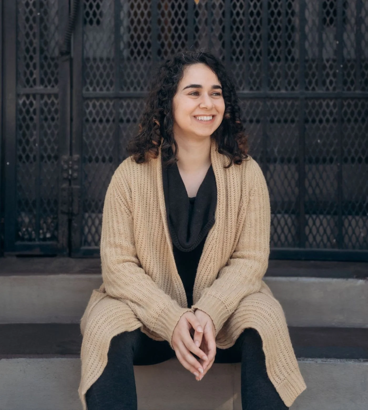 Smiling autistic therapist sitting on stairs outside her therapy office, offering autism therapy and neurodivergence affirming therapy for autistic adults.