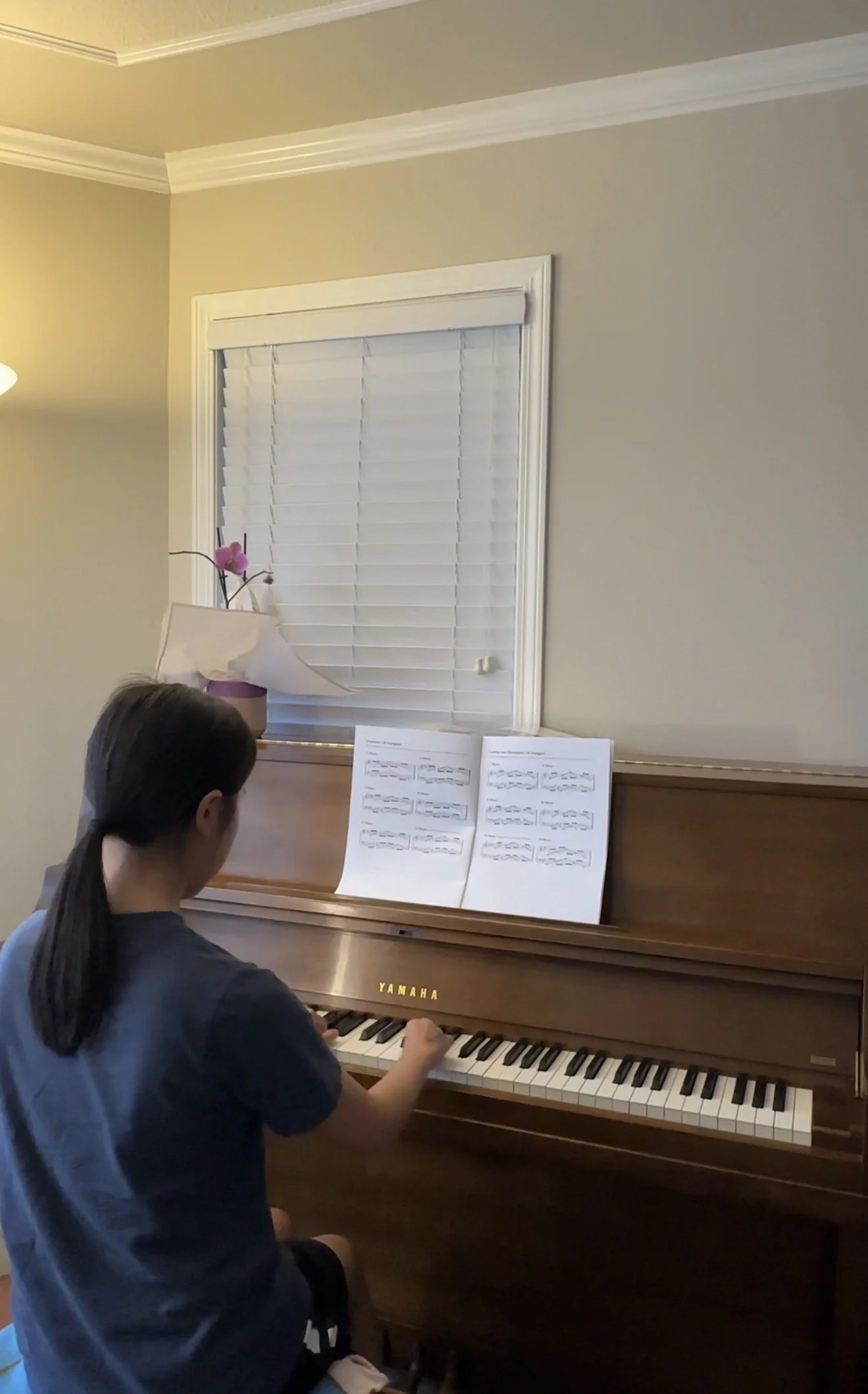 A young girl playing a Yamaha upright piano with sheet music