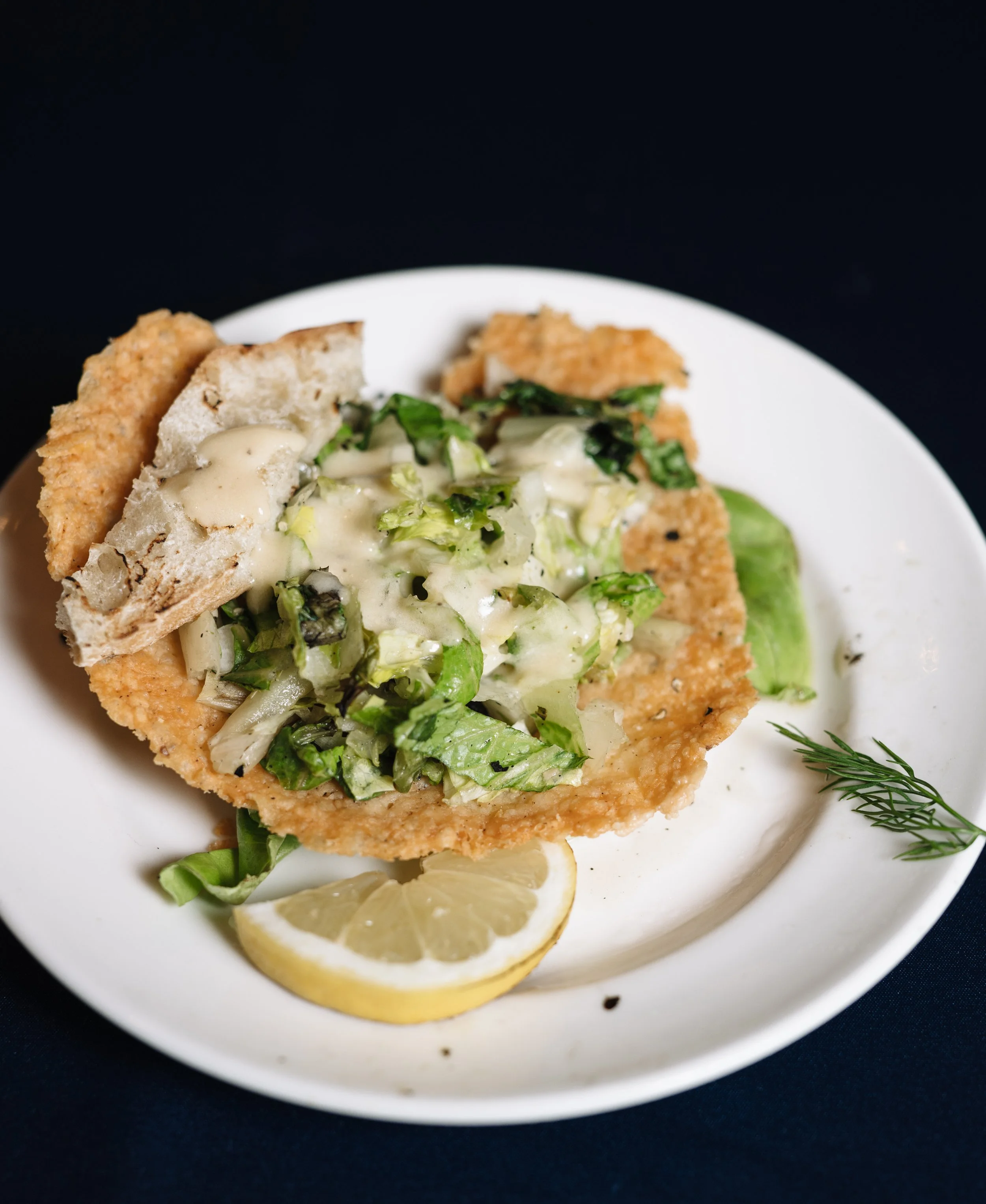 Lemon wedge, fresh dill, and a creamy seafood dish served on a white plate with a black background.