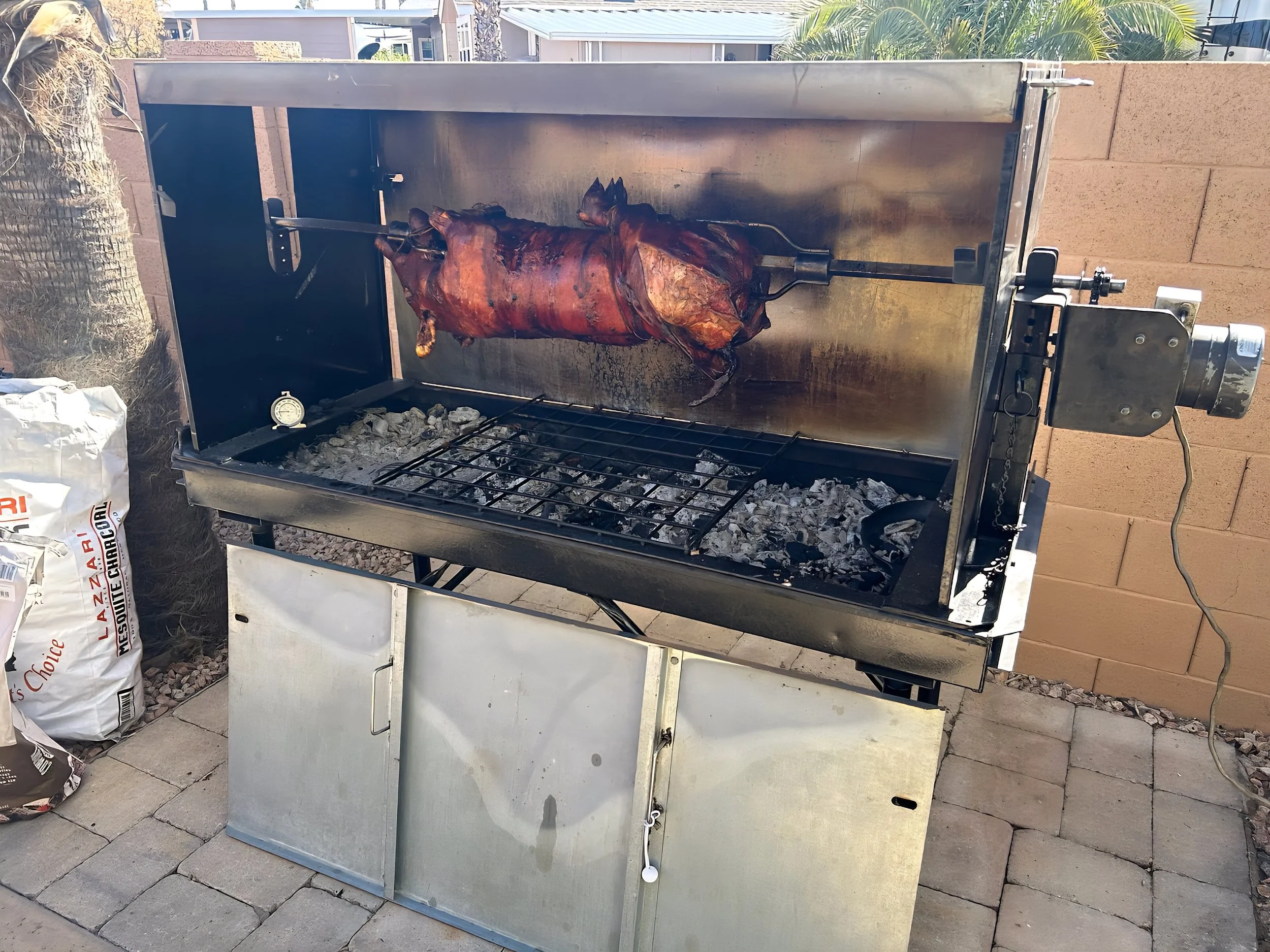 Whole pig roasting on an outdoor rotisserie grill for a party, barbecue or catered event in Phoenix, Arizona.