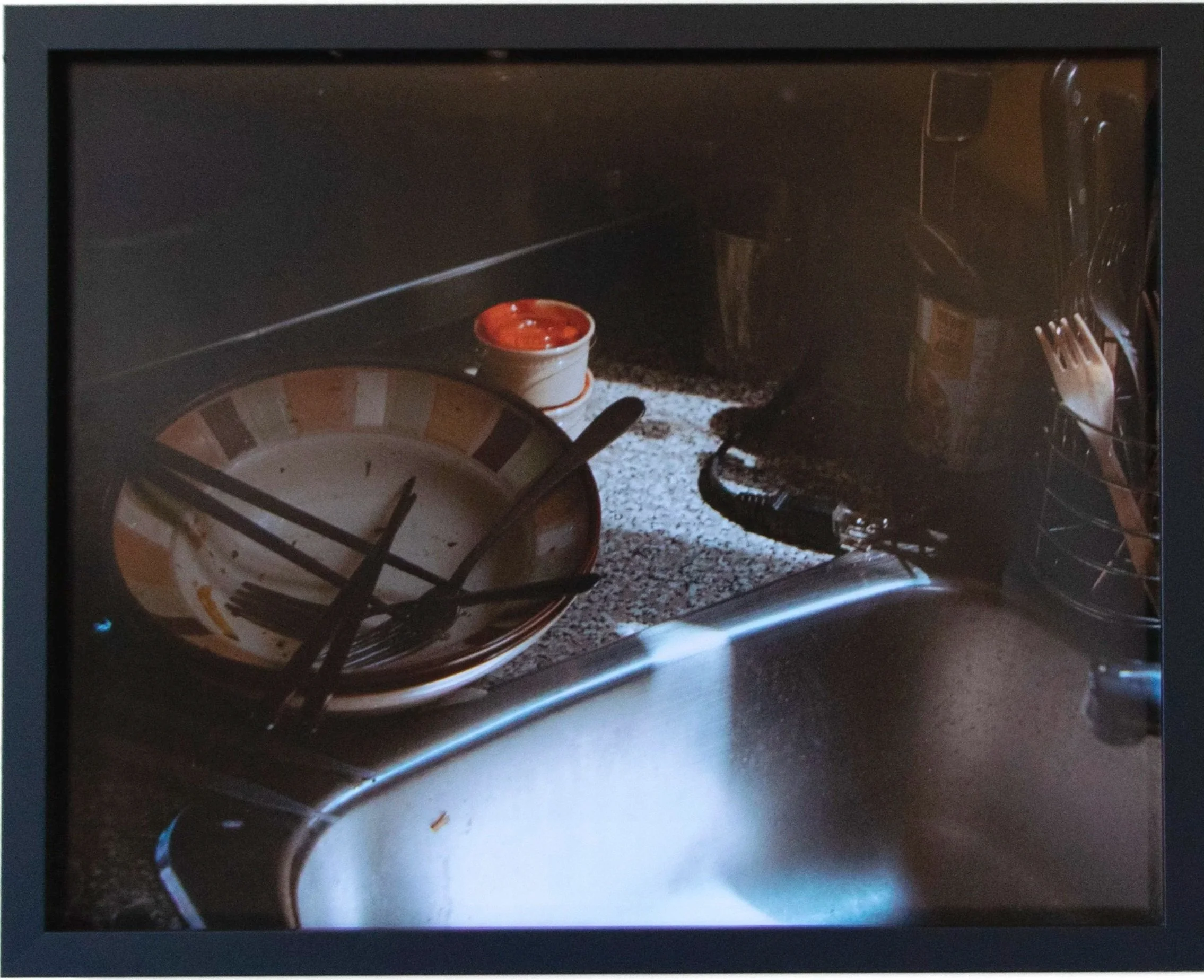 A kitchen sink with a plate and a small bowl of salsa aside.