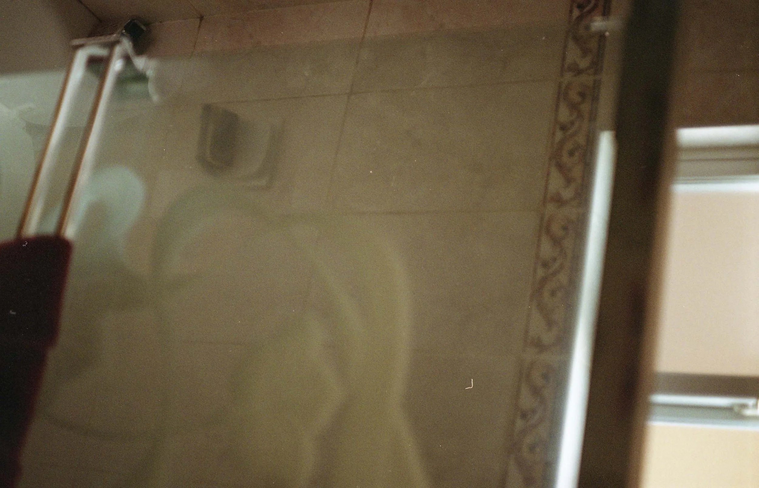 A blurry photo of a bathroom with a shower, and a tile border.