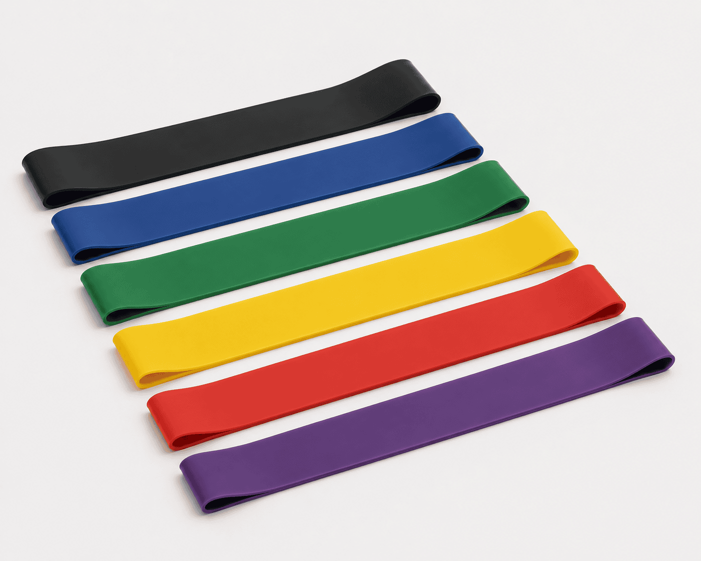 Multiple resistance bands in black, blue, green, yellow, red, and purple laid out on a white surface.
