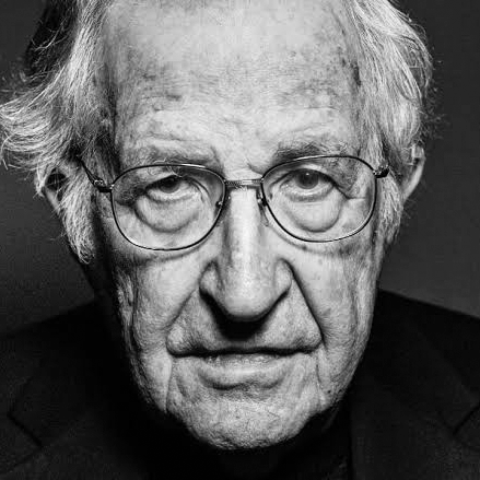 Close-up black and white portrait of an elderly man with glasses, gray hair, and a serious expression.