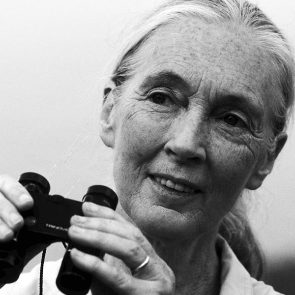 Old woman with gray hair holding binoculars, smiling in black and white.