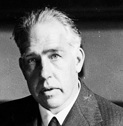 Black and white portrait of a man with light-colored hair, wearing a suit and tie.