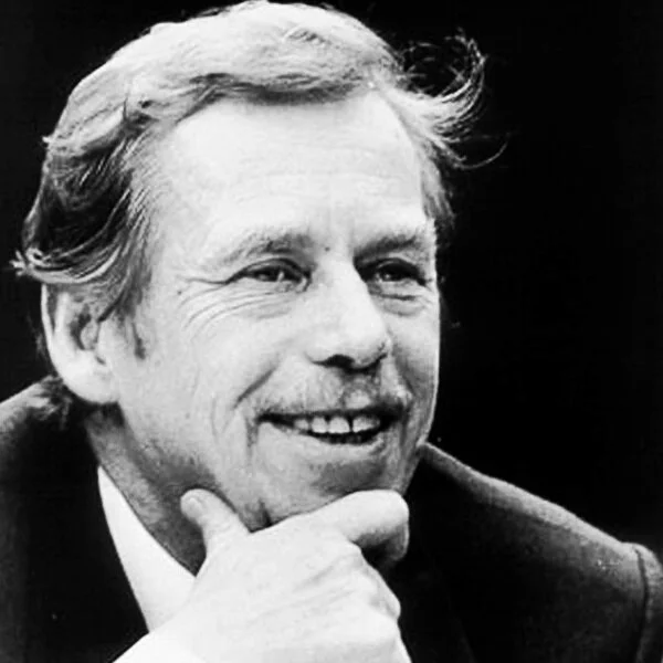Black and white portrait of a smiling man with wavy hair, resting his chin on his hand.
