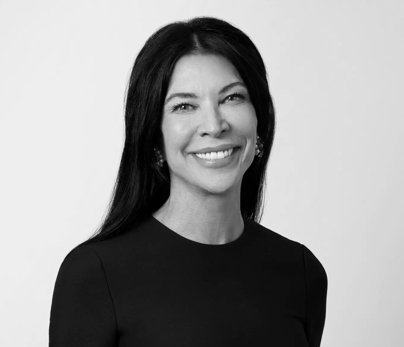Black and white portrait of Dr. Elizabeth Poynor with long dark hair, smiling, wearing earrings and a black top, against a plain background.