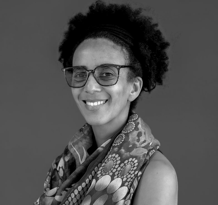 Black and white portrait of Timnit Gebru in a patterned scarf draped over her shoulder against a plain background.