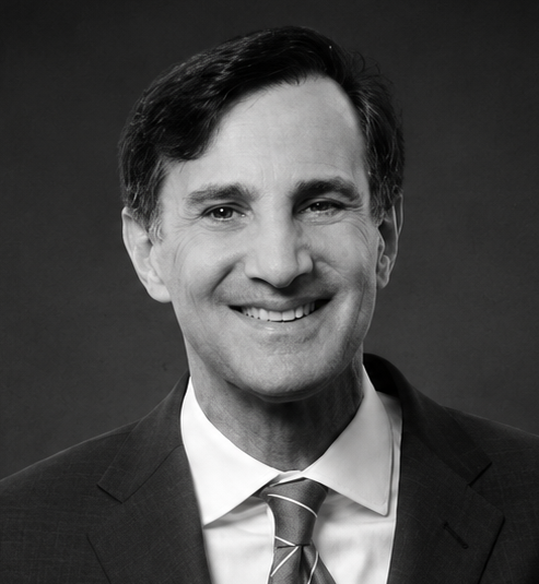 Black and white professional headshot of Ron J. Daniels in a suit and tie.