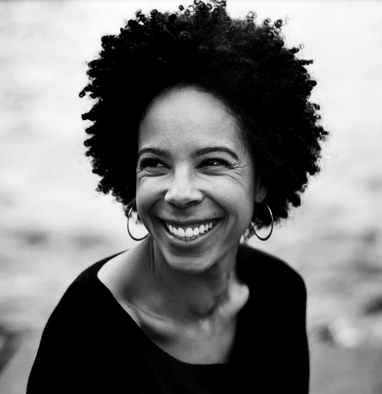 Black and white photo of Ayana Elizabeth Johnson looking to her right, wearing hoop earrings and a black top.
