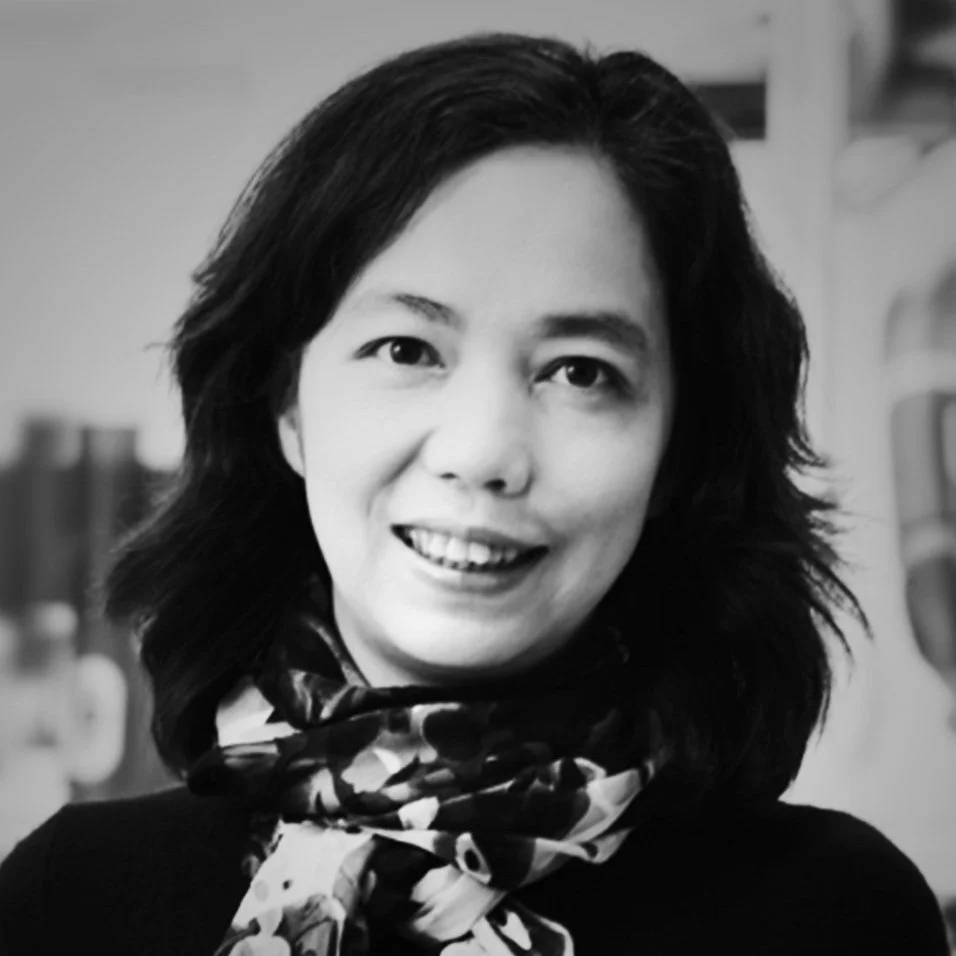 Black and white portrait of Dr. Fei-Fei Li, smiling at the camera, wearing a scarf with a floral pattern.