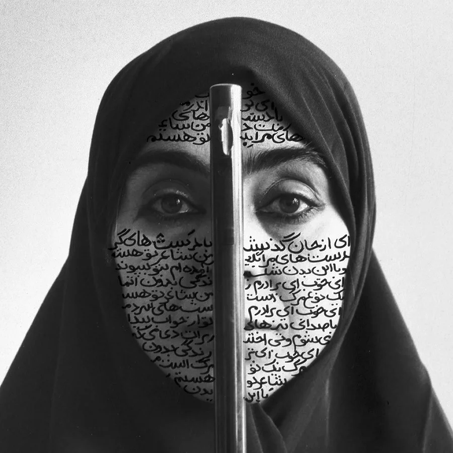 Black and white photo of a woman with her face partially covered by a metallic object, with Persian text written over her face and head, wearing a headscarf and looking directly at the camera.