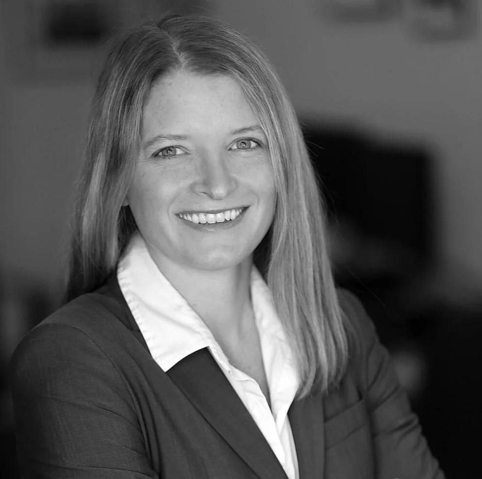 Headshot of a smiling LAURA SCHIFTER, wearing a business suit and white shirt.