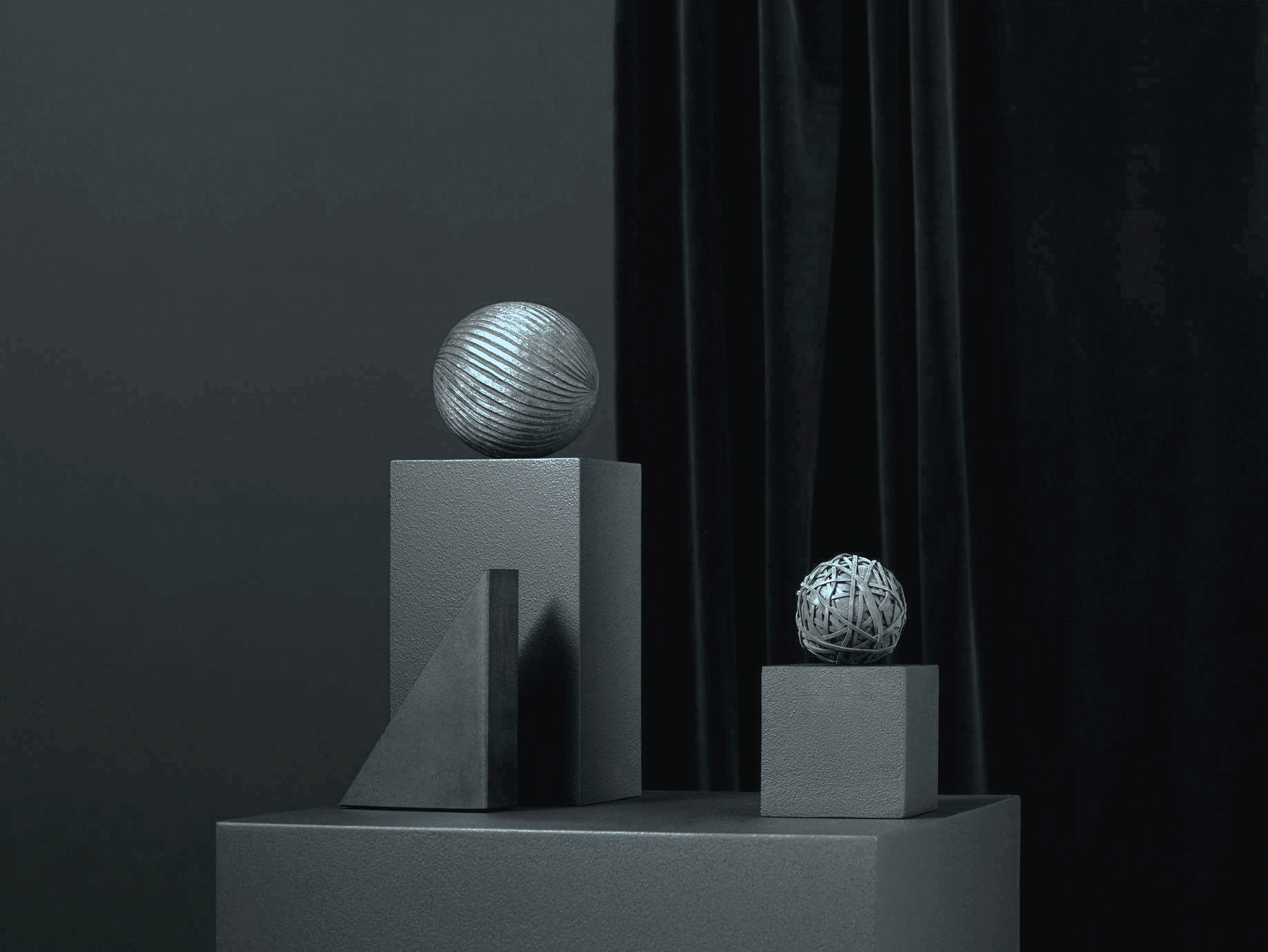 Artistic display of three textured spheres placed on various minimalist pedestals against a dark background, with a black curtain partially visible on the right.