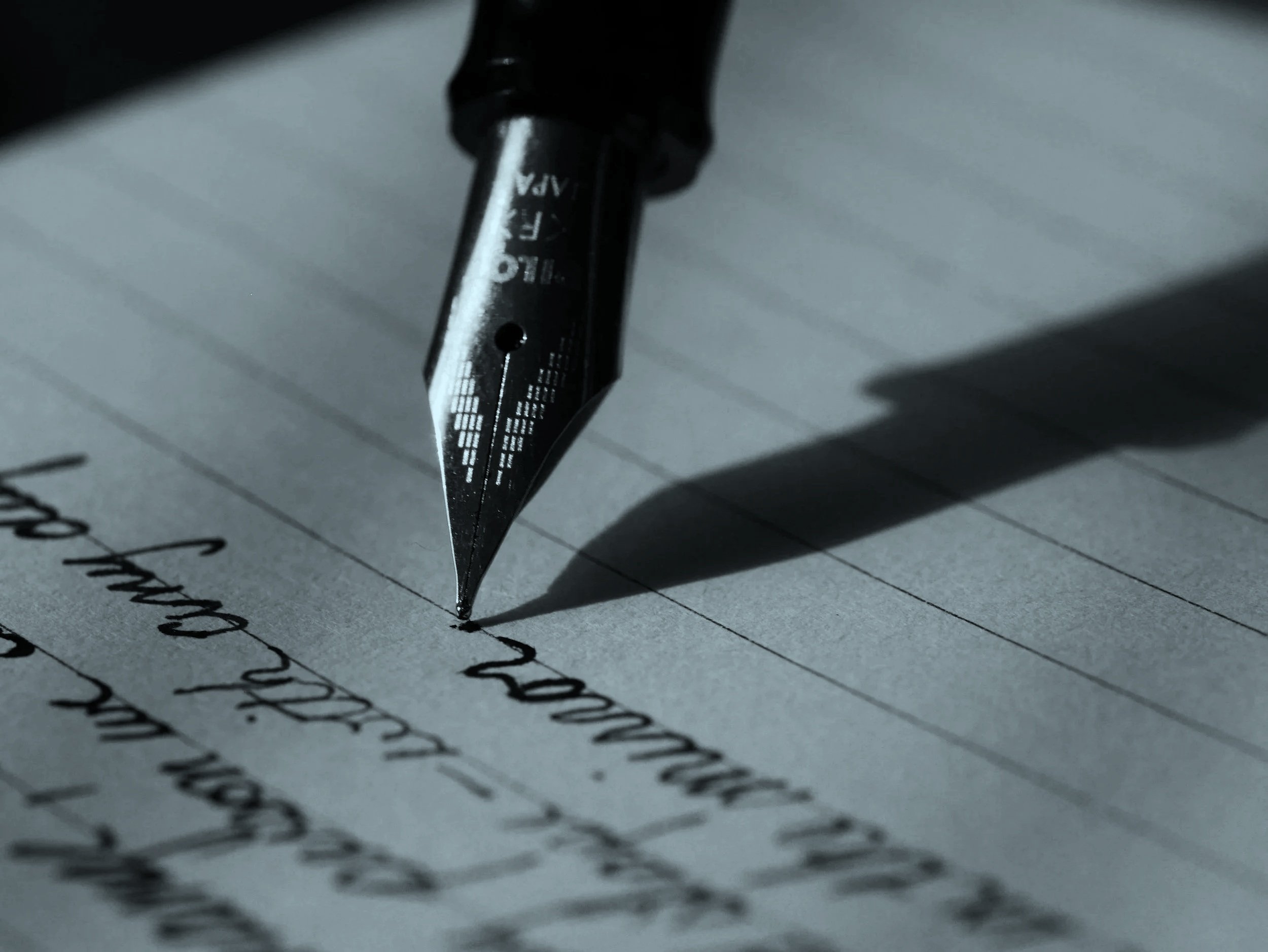 Close-up of a fountain pen writing on lined paper. An image that represents information security policy and procedure drafting.