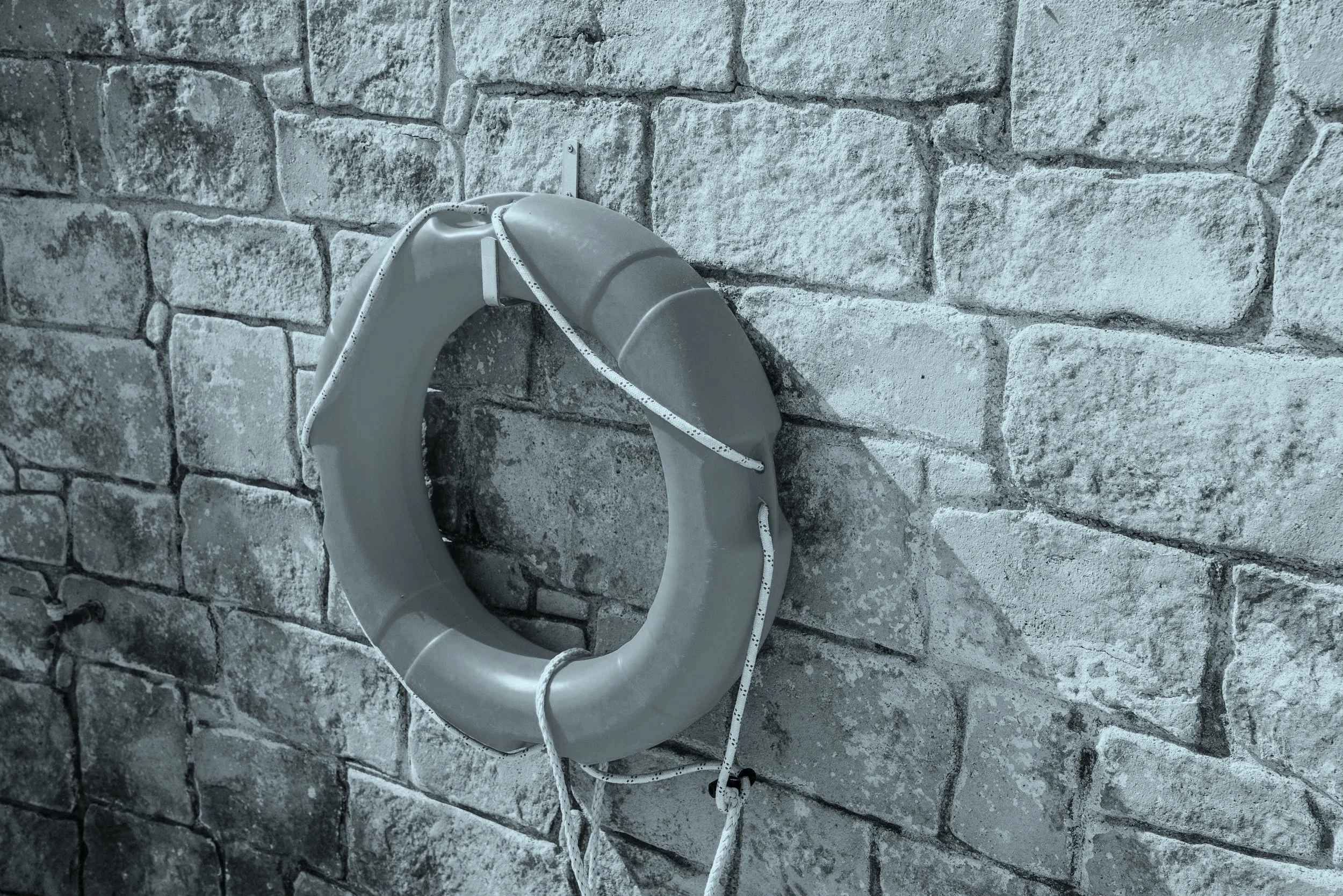 A life preserver or safety buoy in beige color placed on a stone-tile patterned wall in the background. An image that represents business continuity and disaster recovery planning.