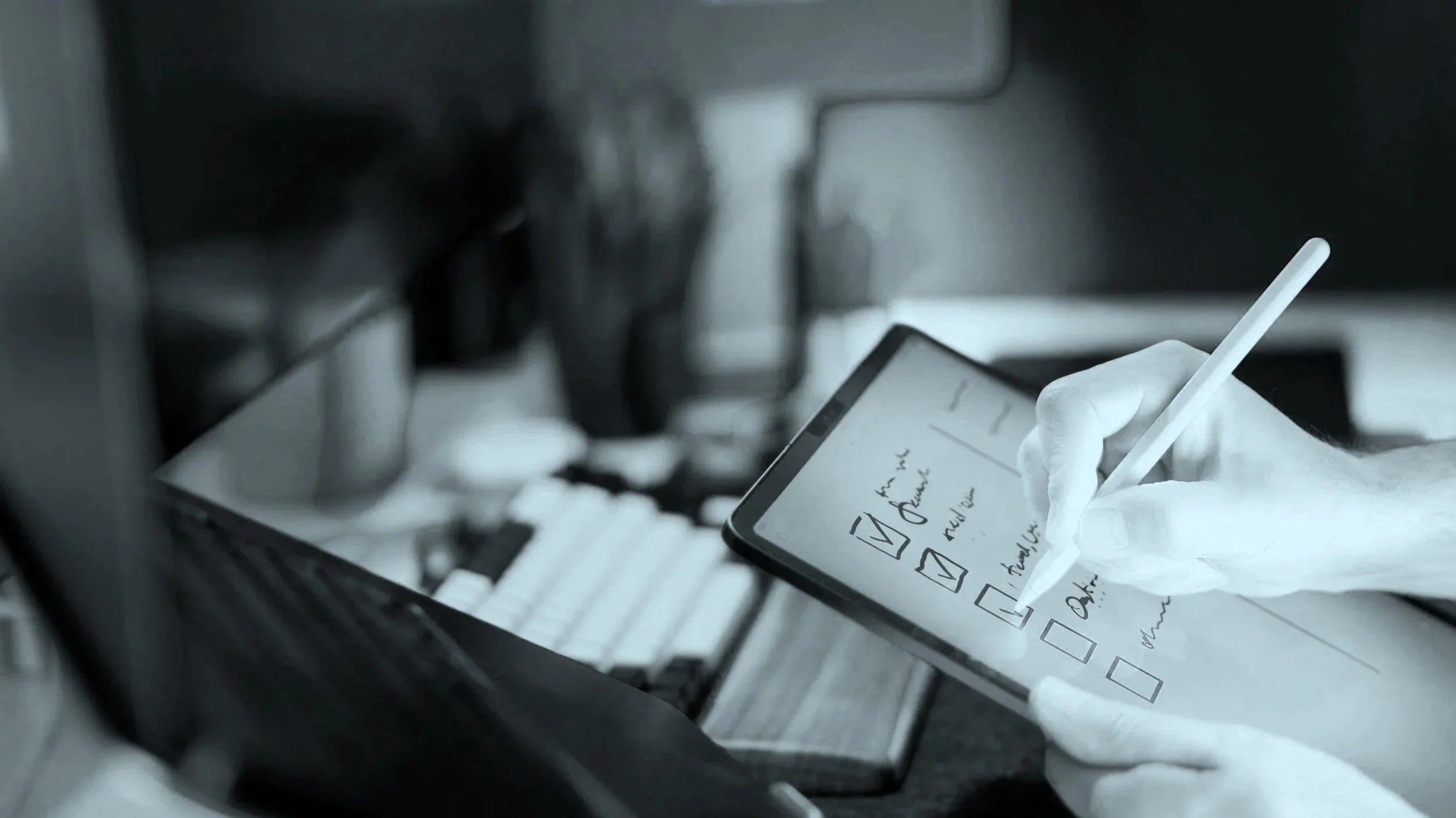 Close-up of a person writing on a smartphone with a stylus, with a paper checklist and crumpled tissue nearby, in an office setting. An image that represents ongoing ISMS management.