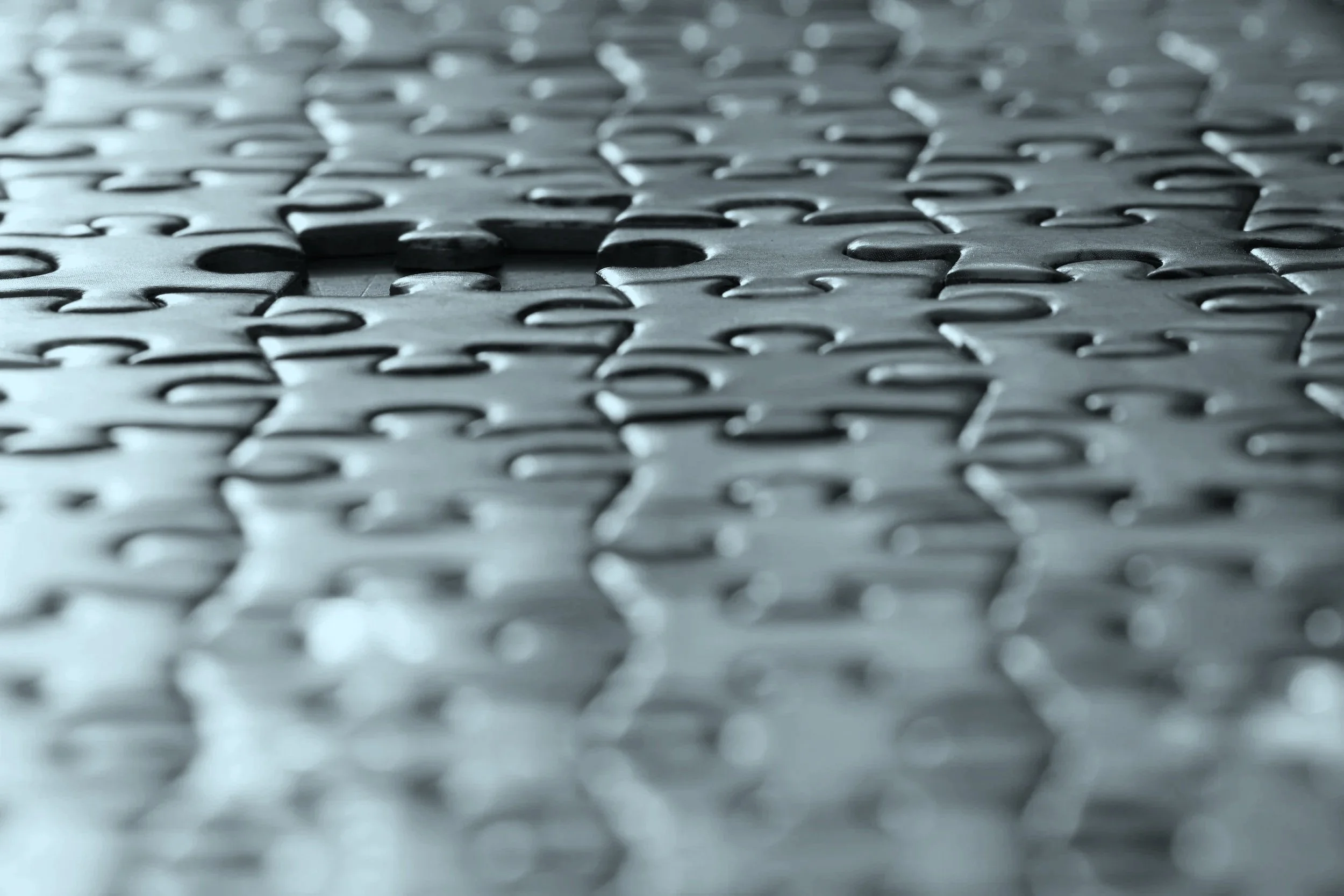Close-up view of a metallic jigsaw puzzle laid flat on a surface. An image that represents cybersecurity maturity assessments and cybersecurity audit preparation.