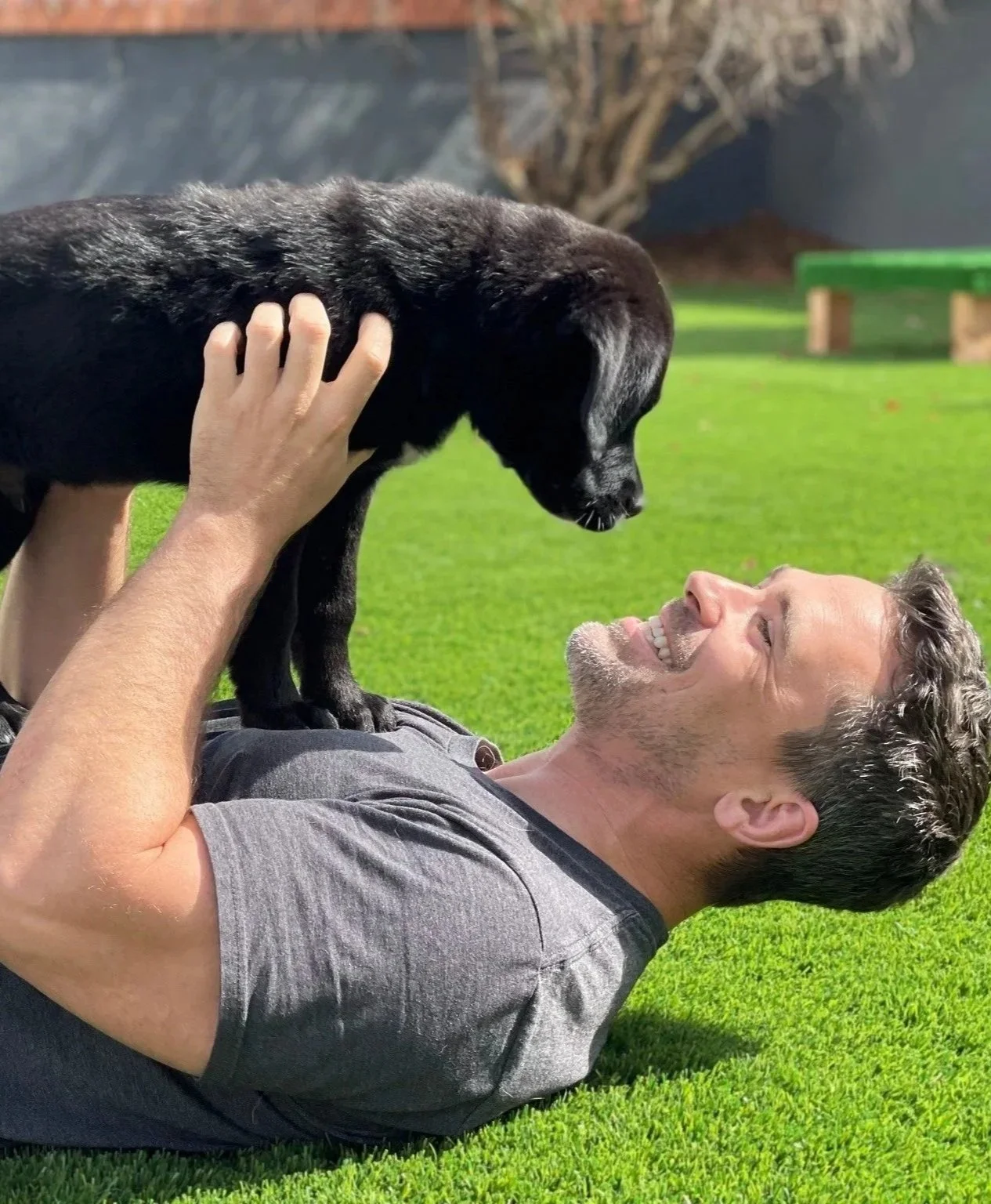Professional dog trainer Nate Schoemer working with a black Labrador puppy during puppy socialization and relationship-building exercises.