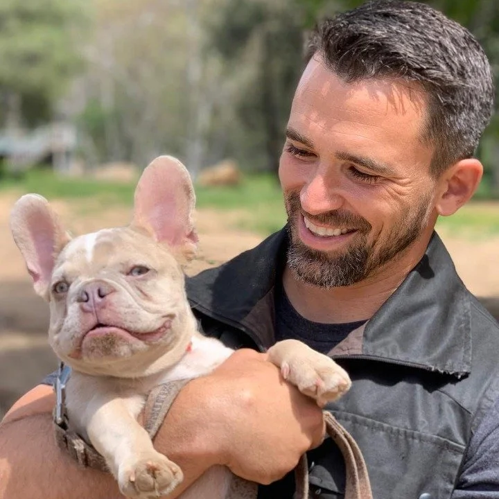 Nate Schoemer interacting with a French Bulldog puppy during relationship-building and puppy training.