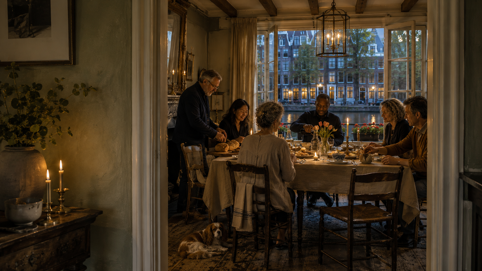 Friends gather around a candlelit table in an Amsterdam canal house at blue hour, with open windows, canal reflections, simple Dutch fare, and a Cavalier King Charles Spaniel beneath the table.