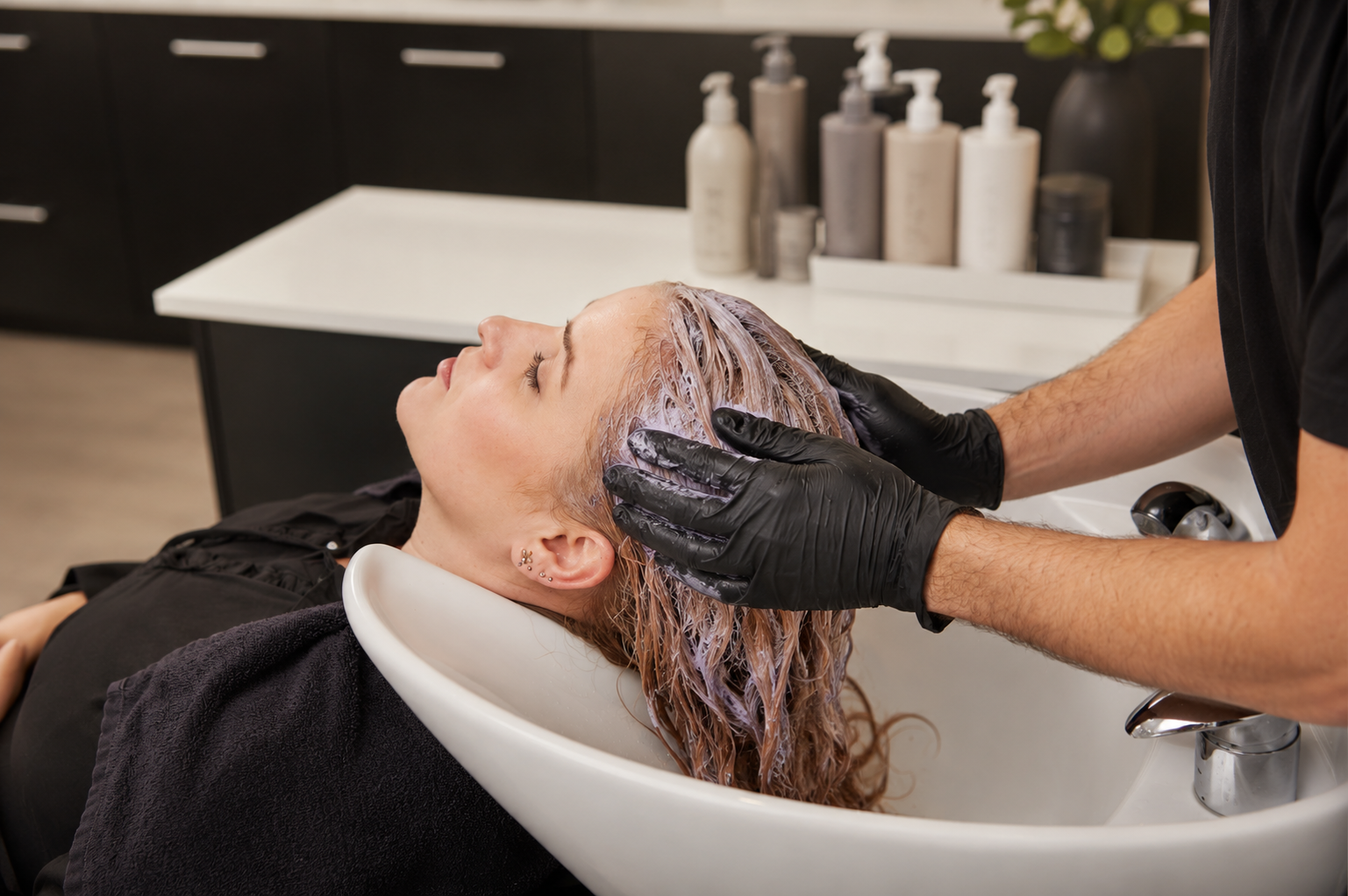 Professional salon gloss treatment at the shampoo bowl illustrates how toners and color-refresh services restore shine, tone, and vibrancy between full hair color appointments.