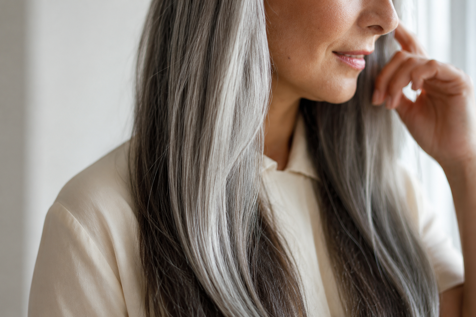 Elegant close-up editorial portrait of naturally transitioning brunette and silver hair, illustrating how hair color decisions evolve after 45 as changing texture, contrast, and gray influence flattering color choices.