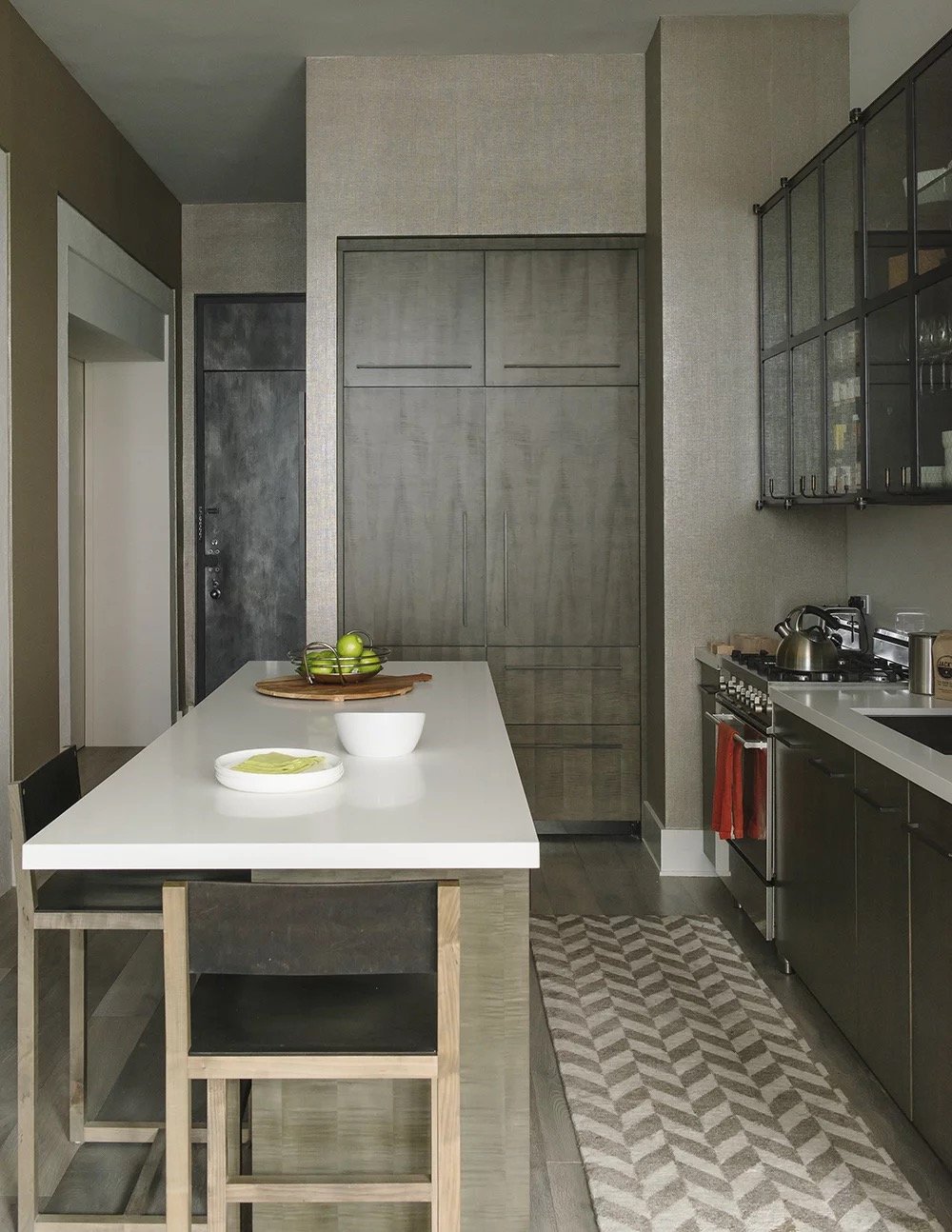 Bond St kitchen with a white island, wood stools, dark cabinetry and herringbone floor