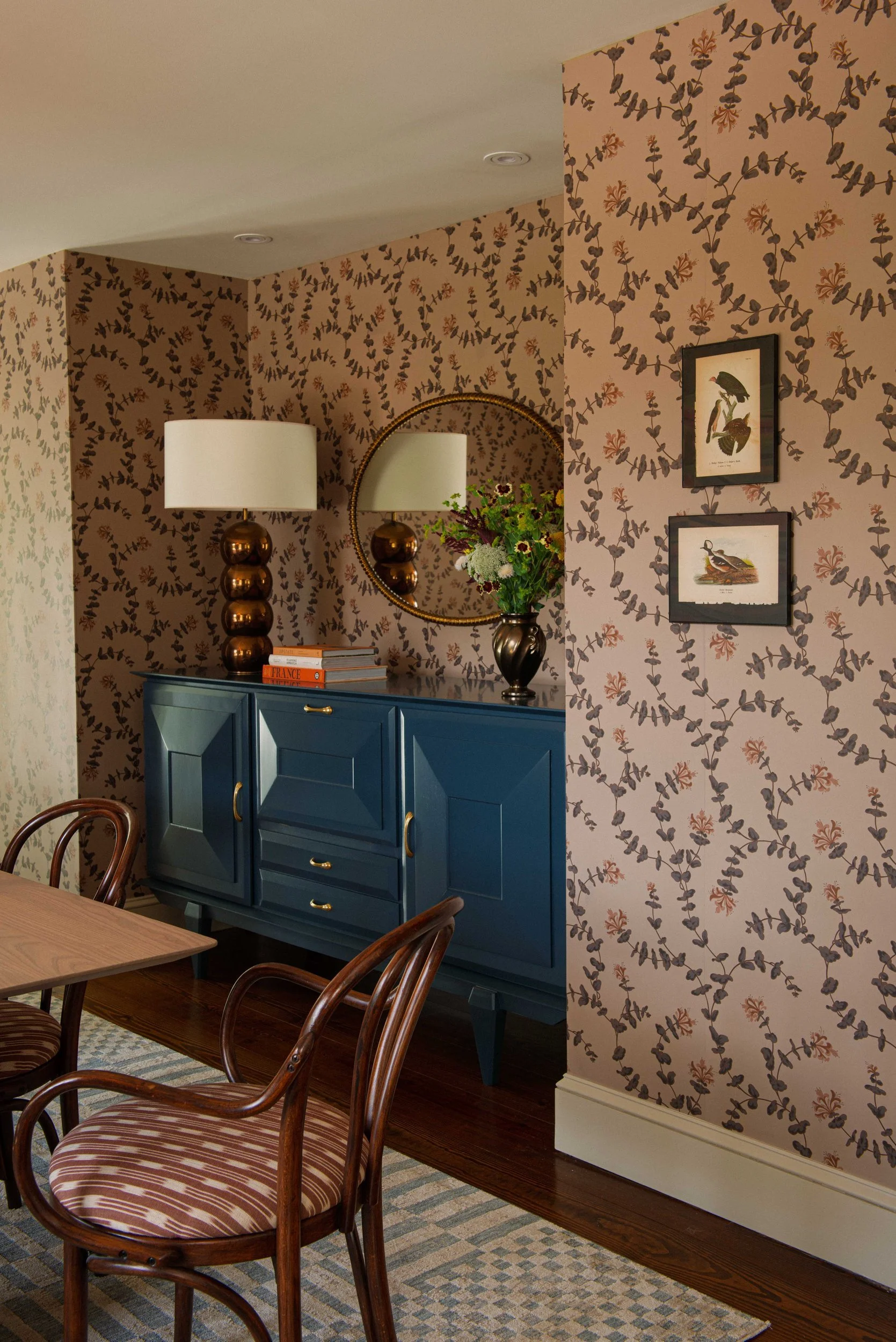 Silvernails dining room corner with leaf-print wallpaper, a navy cabinet and bentwood chairs