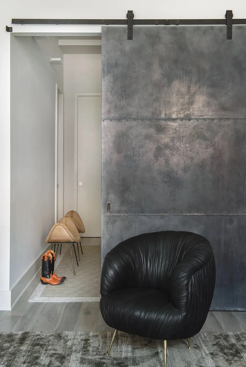 Bond St entry with a black leather lounge chair and a steel sliding barn door
