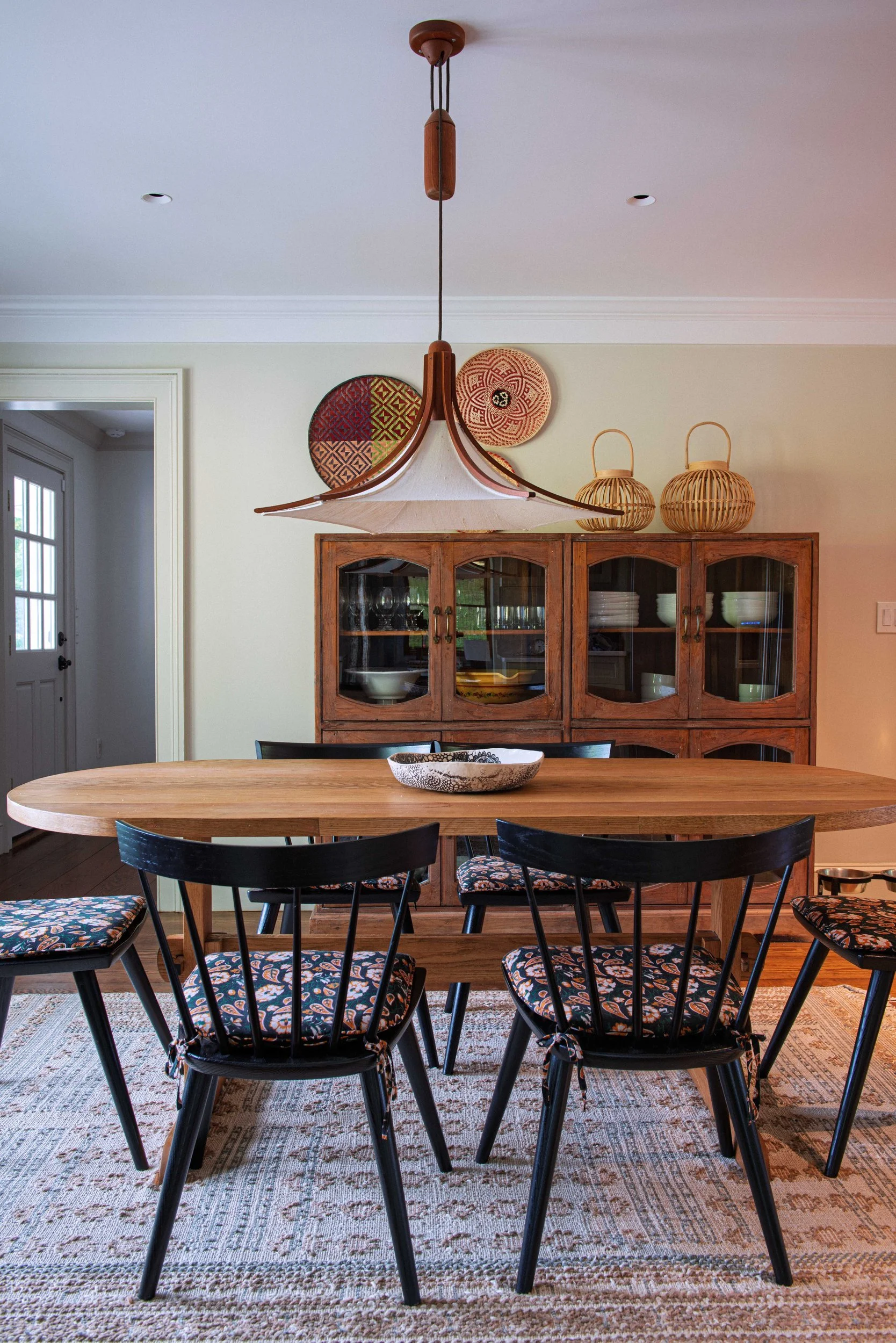 Silvernails dining room with a round wood table, black Windsor chairs and a woven pendant light