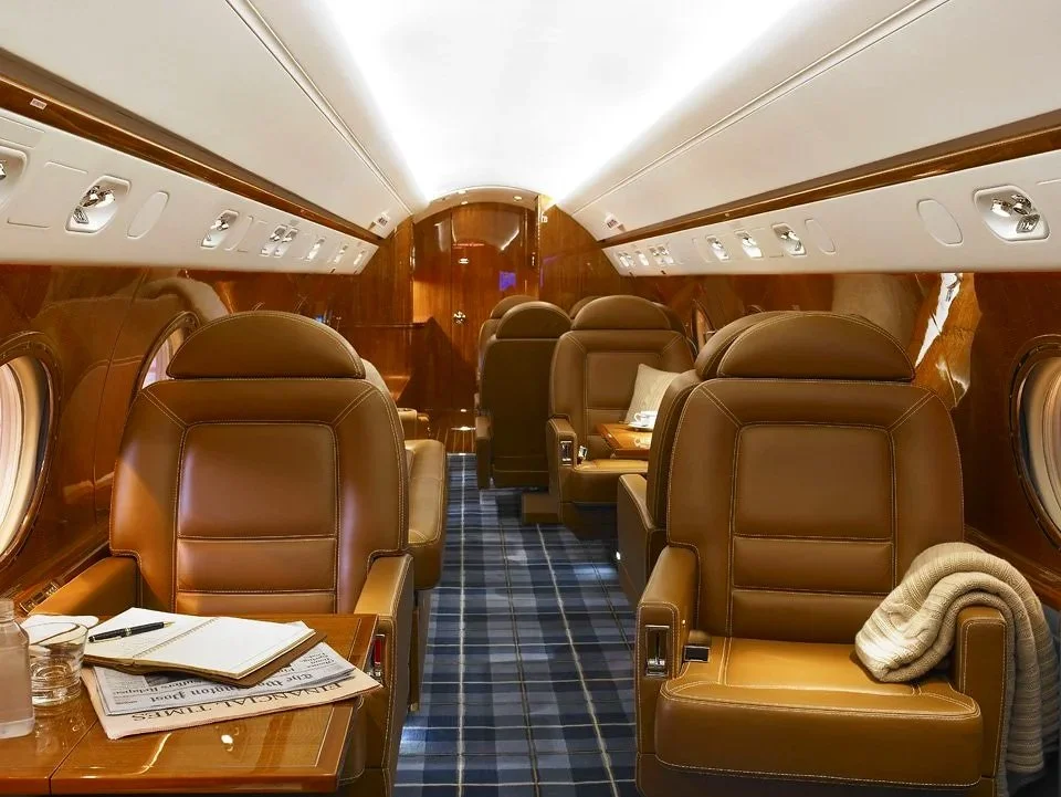 Gulfstream G4 private jet cabin with tan leather club seats and blue plaid carpet