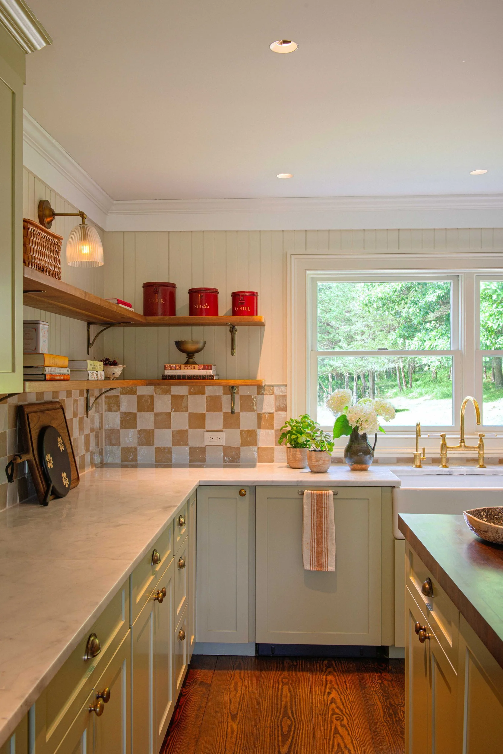 Sage green Silvernails kitchen with brass sconces, open shelves and red canisters