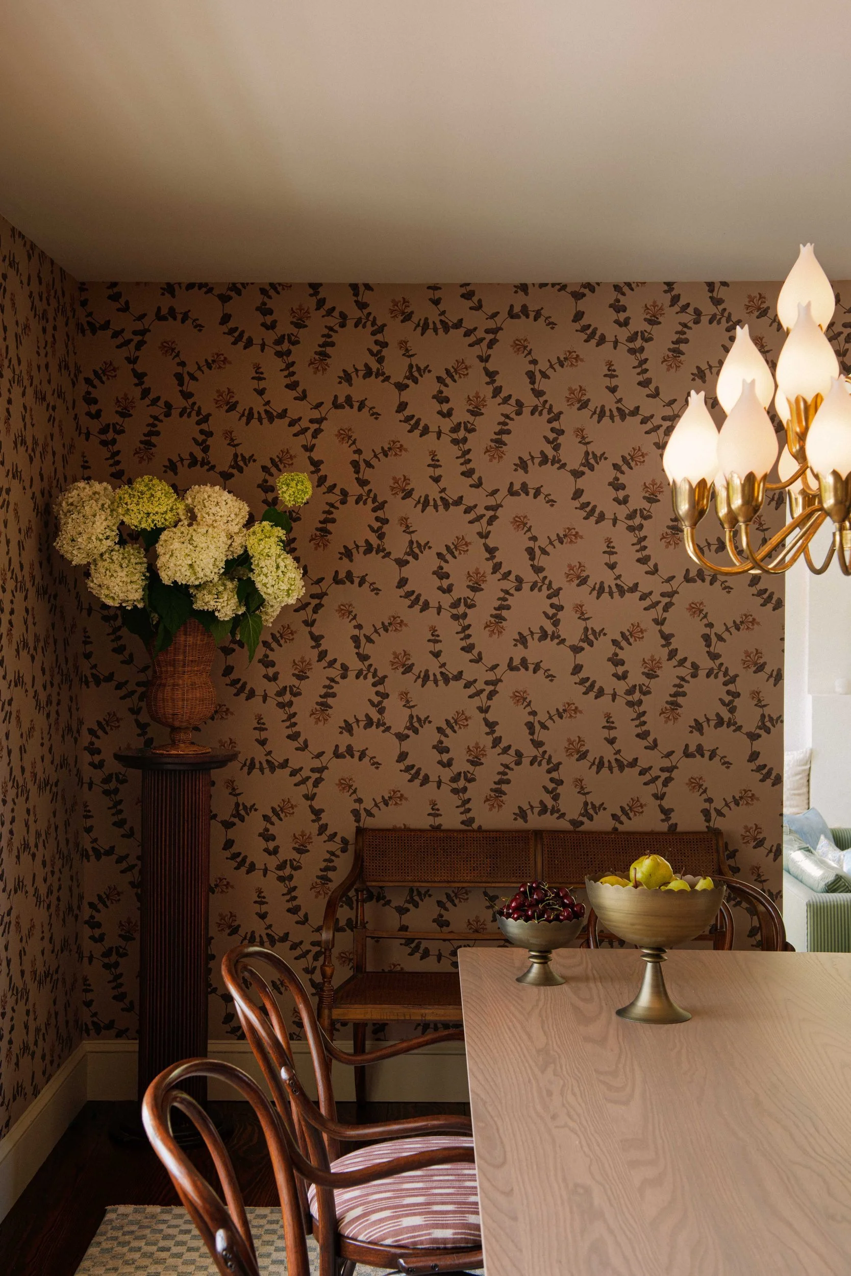 Silvernails dining nook with botanical wallpaper, a crystal sconce and yellow hydrangeas