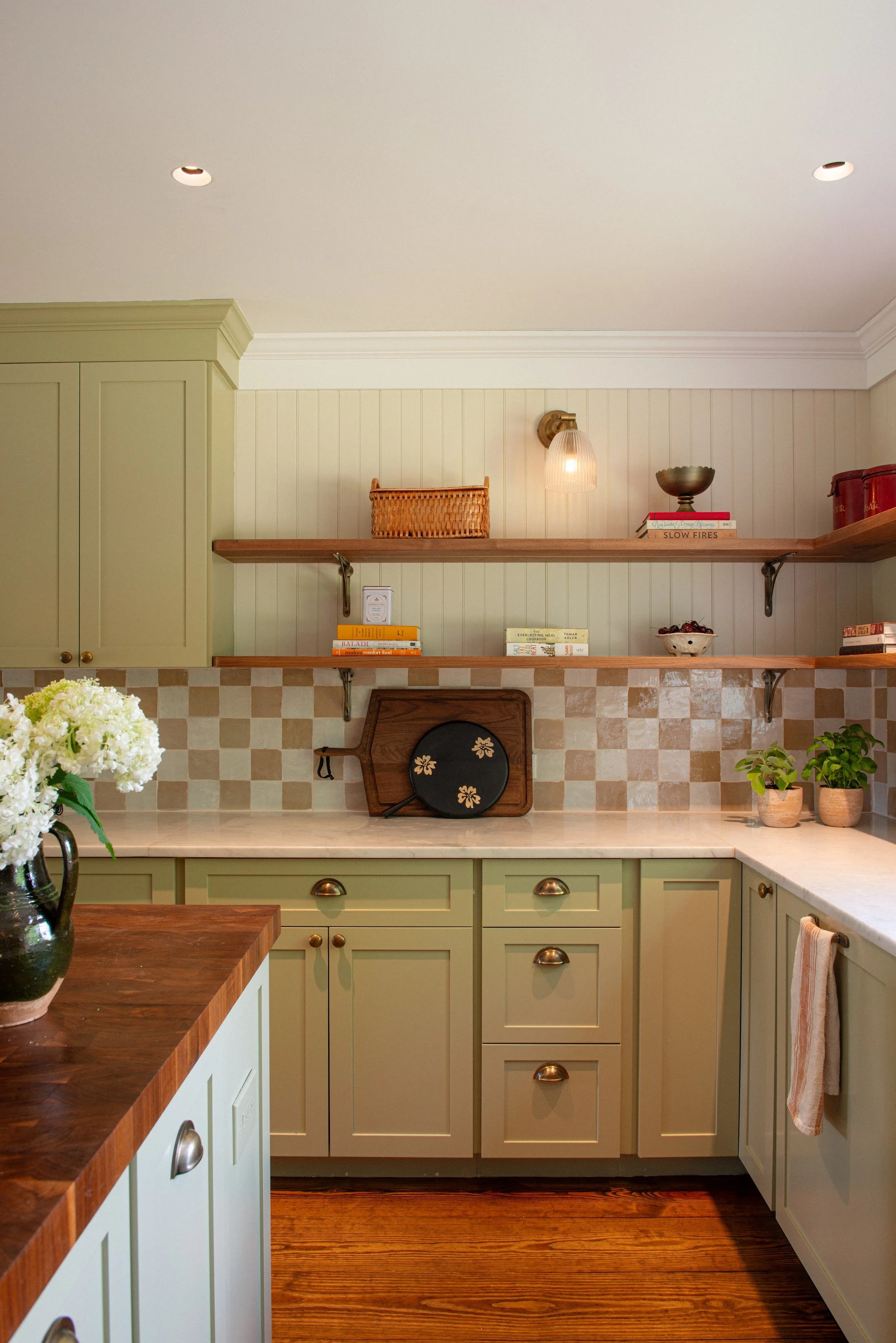 Kitchen with sage green cabinetry, a walnut butcher-block counter and chequered tile backsplash
