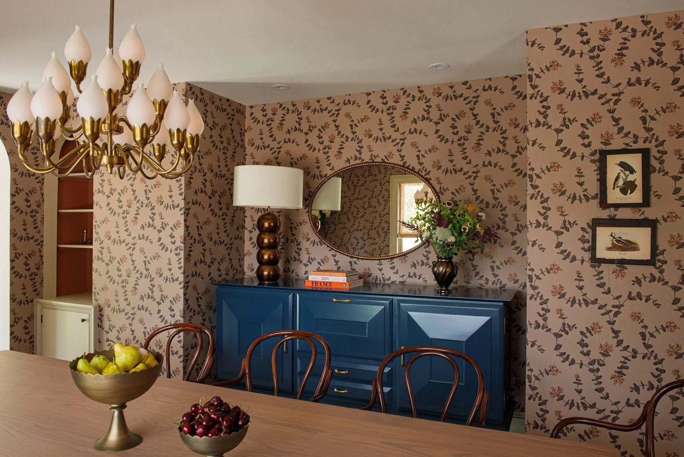 Silvernails dining room with botanical wallpaper, a navy sideboard and brass chandelier