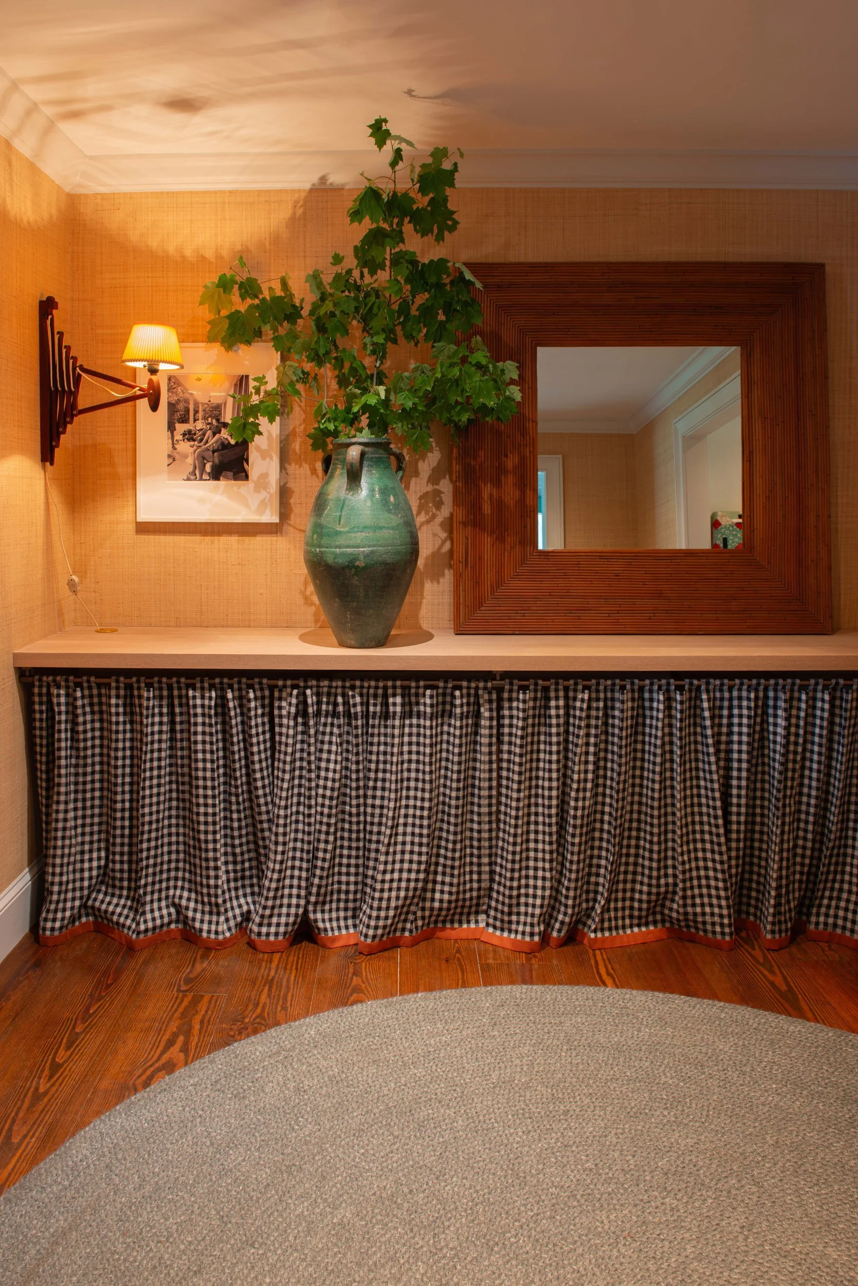 Silvernails hallway with a skirted console, wood mirror, wall sconce and potted greenery