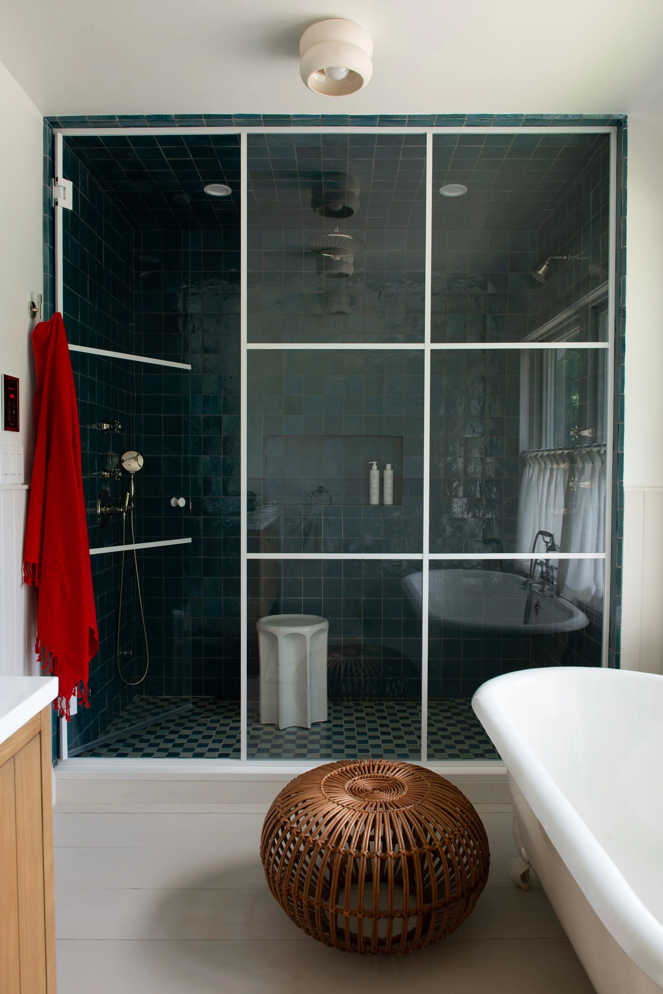 Bathroom with a deep green tiled shower, freestanding tub and woven stool